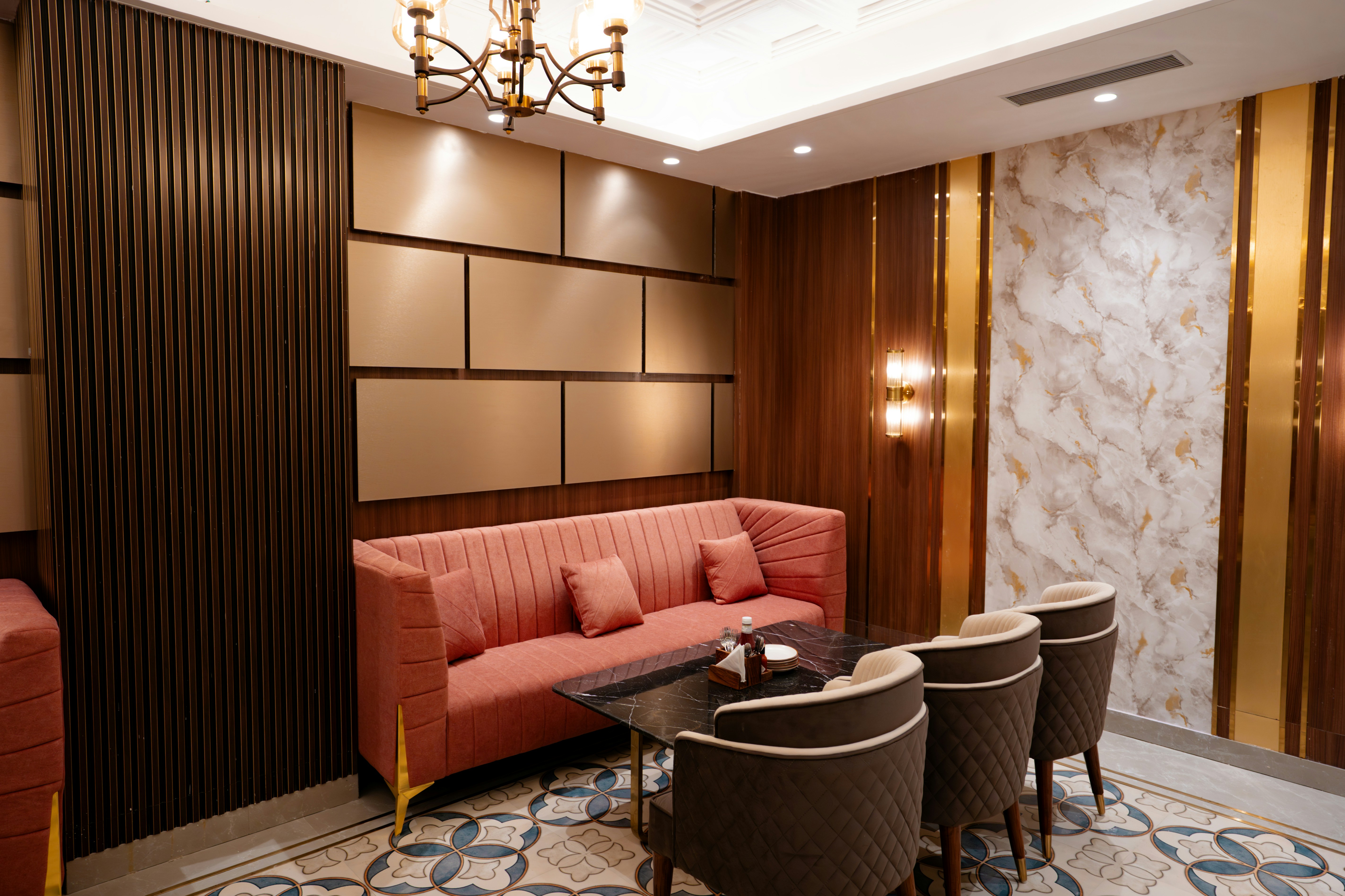 Luxurious lounge with a pink sofa, chairs, and decorative walls.