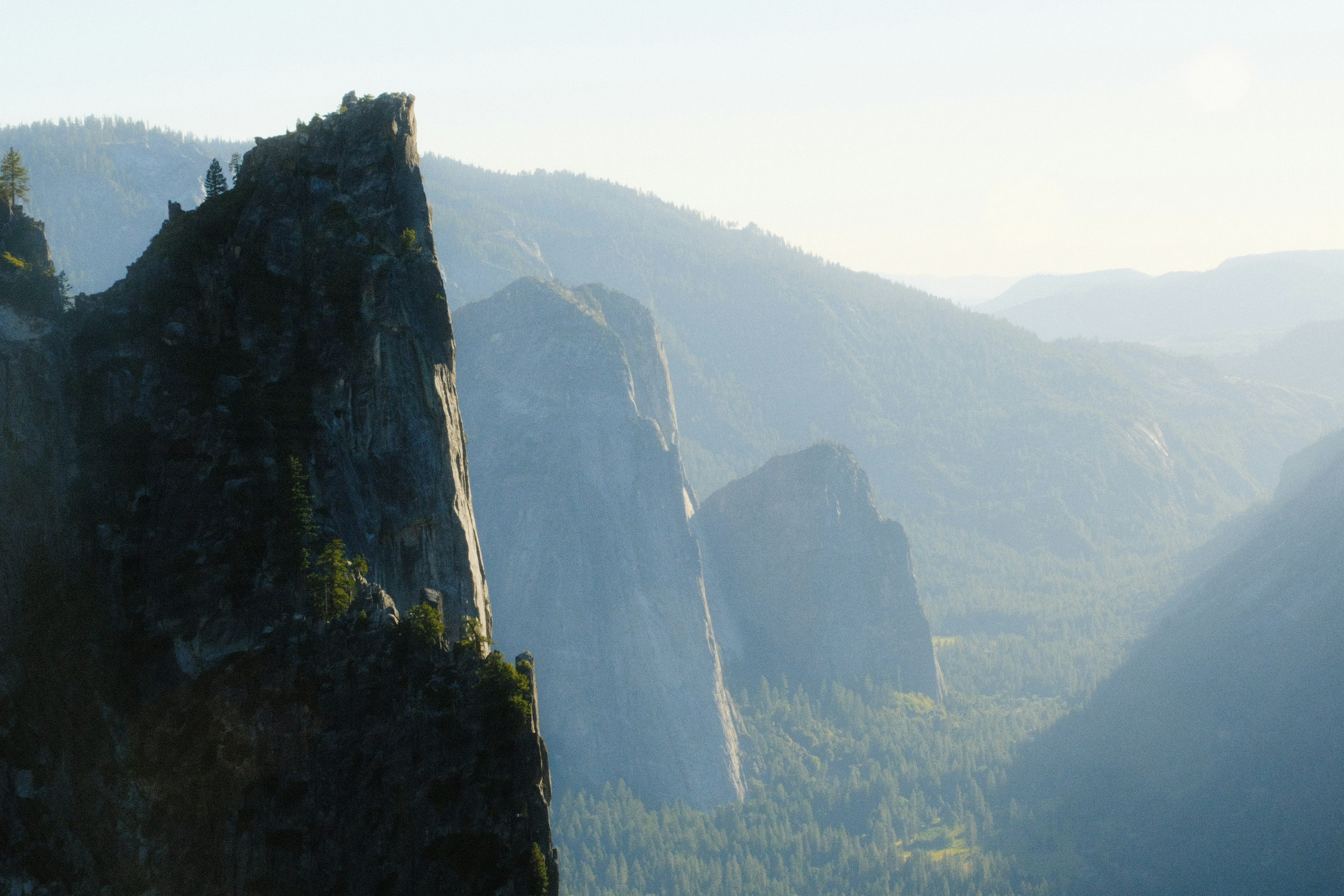 La luce del sole illumina drammatiche scogliere montane e vette lontane e nebbiose.