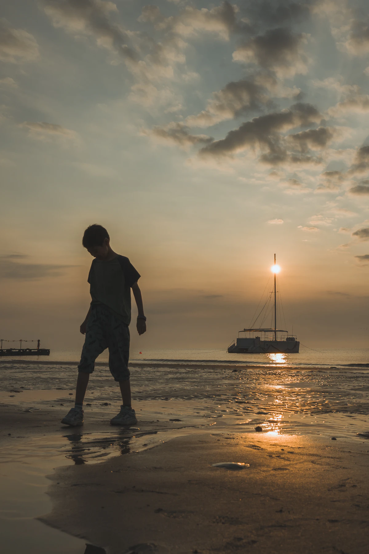 Siluet anak laki-laki berjalan di pantai saat matahari terbenam