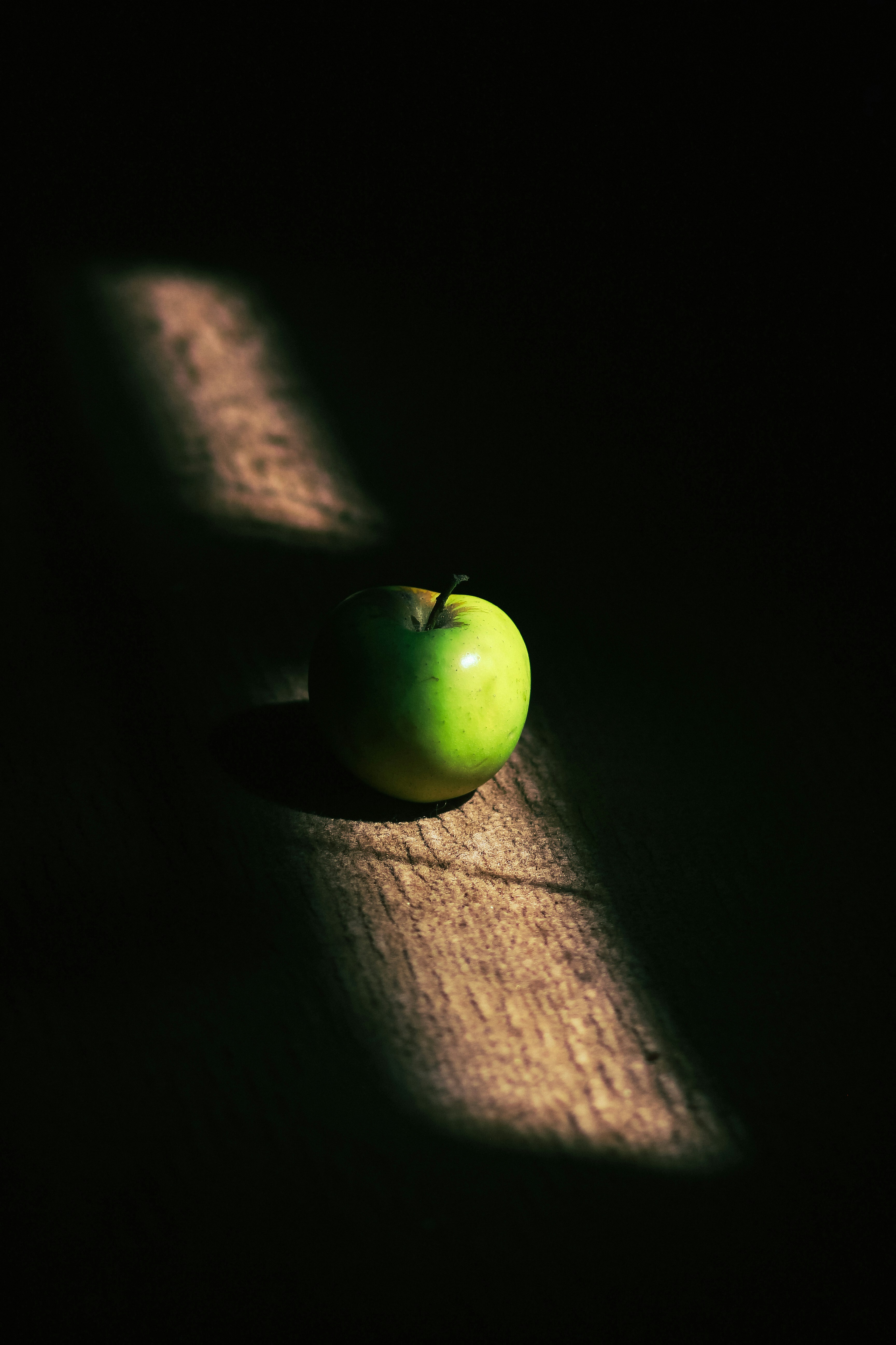 A green apple illuminated by a beam of sunlight