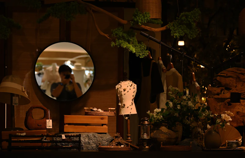 Shop window display with mannequin, mirror, and floral arrangements