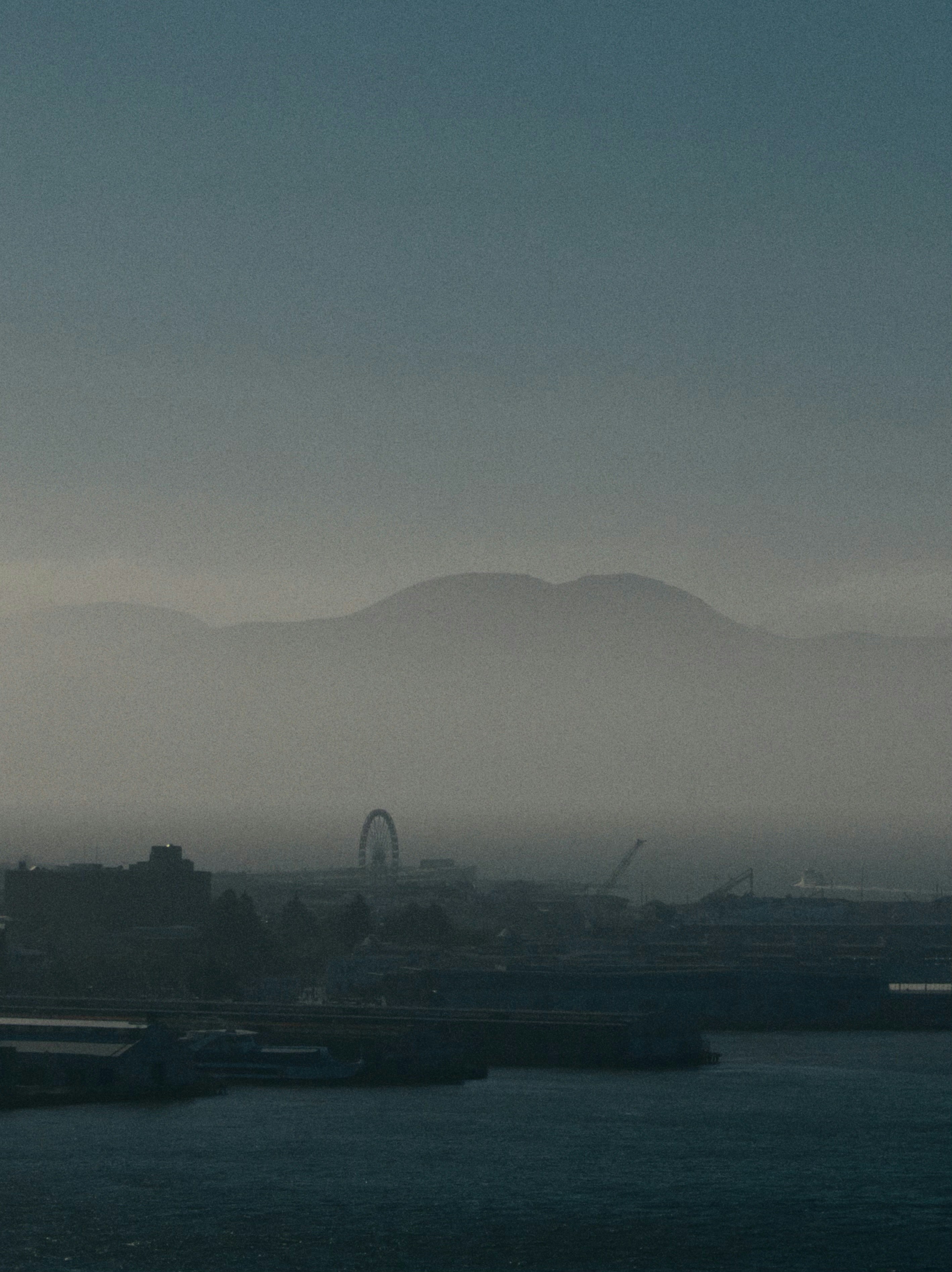 Misty mountains overlooking a city harbor and ship