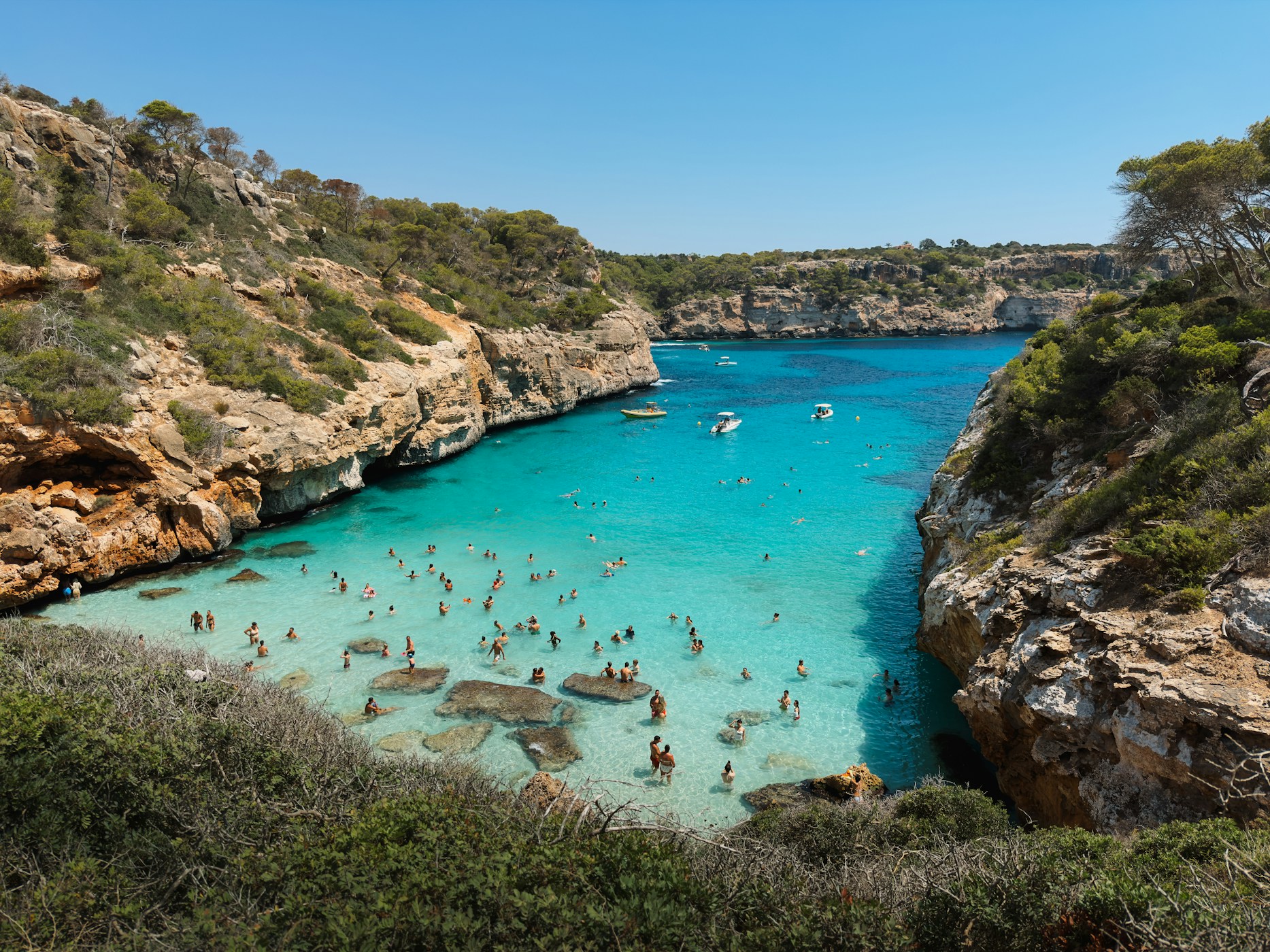 A wide bay of bright blue water between rocky headlands