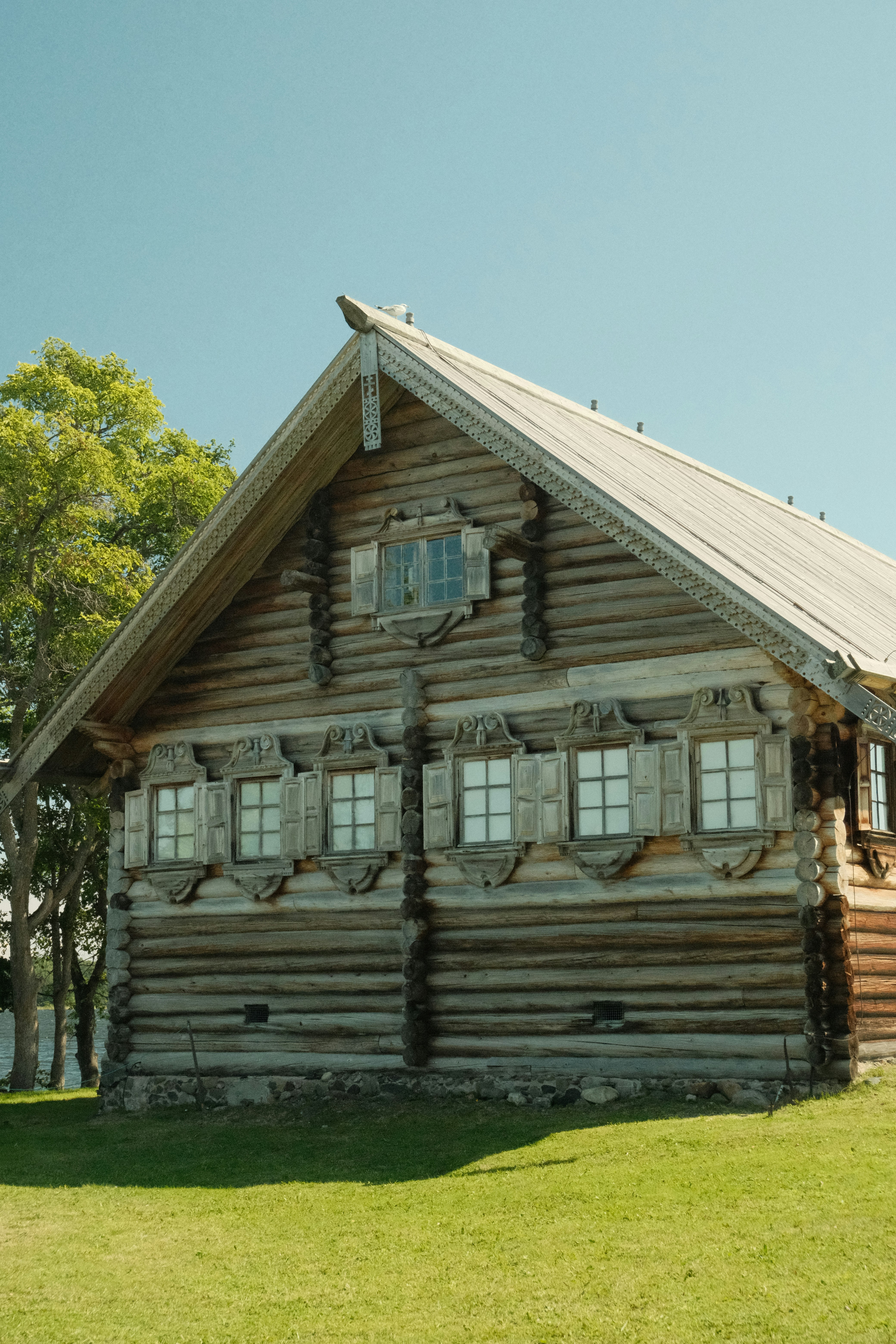 Traditional wooden log house with decorative windows under blue sky.