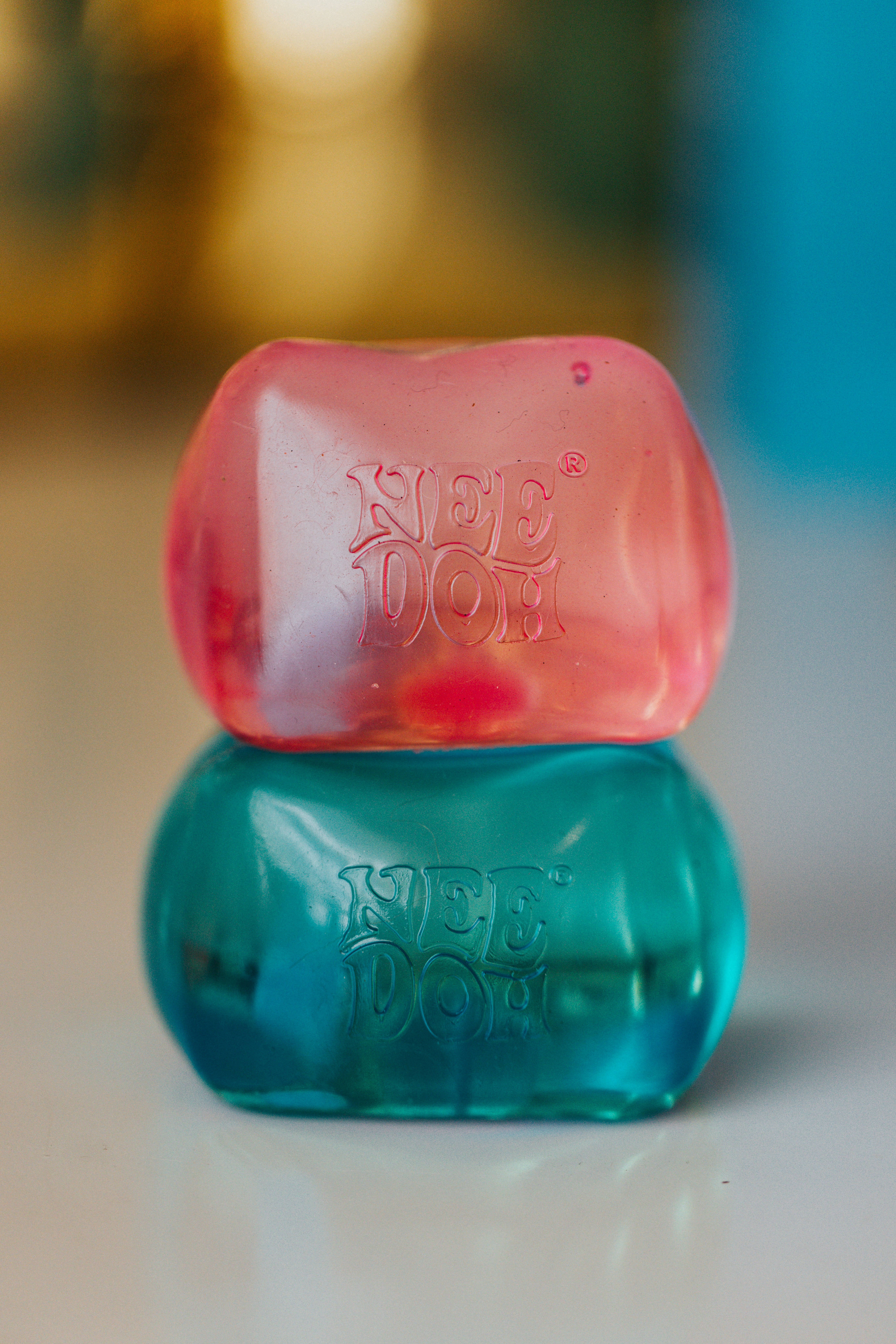 Two stacked needoh stress balls, pink and teal.