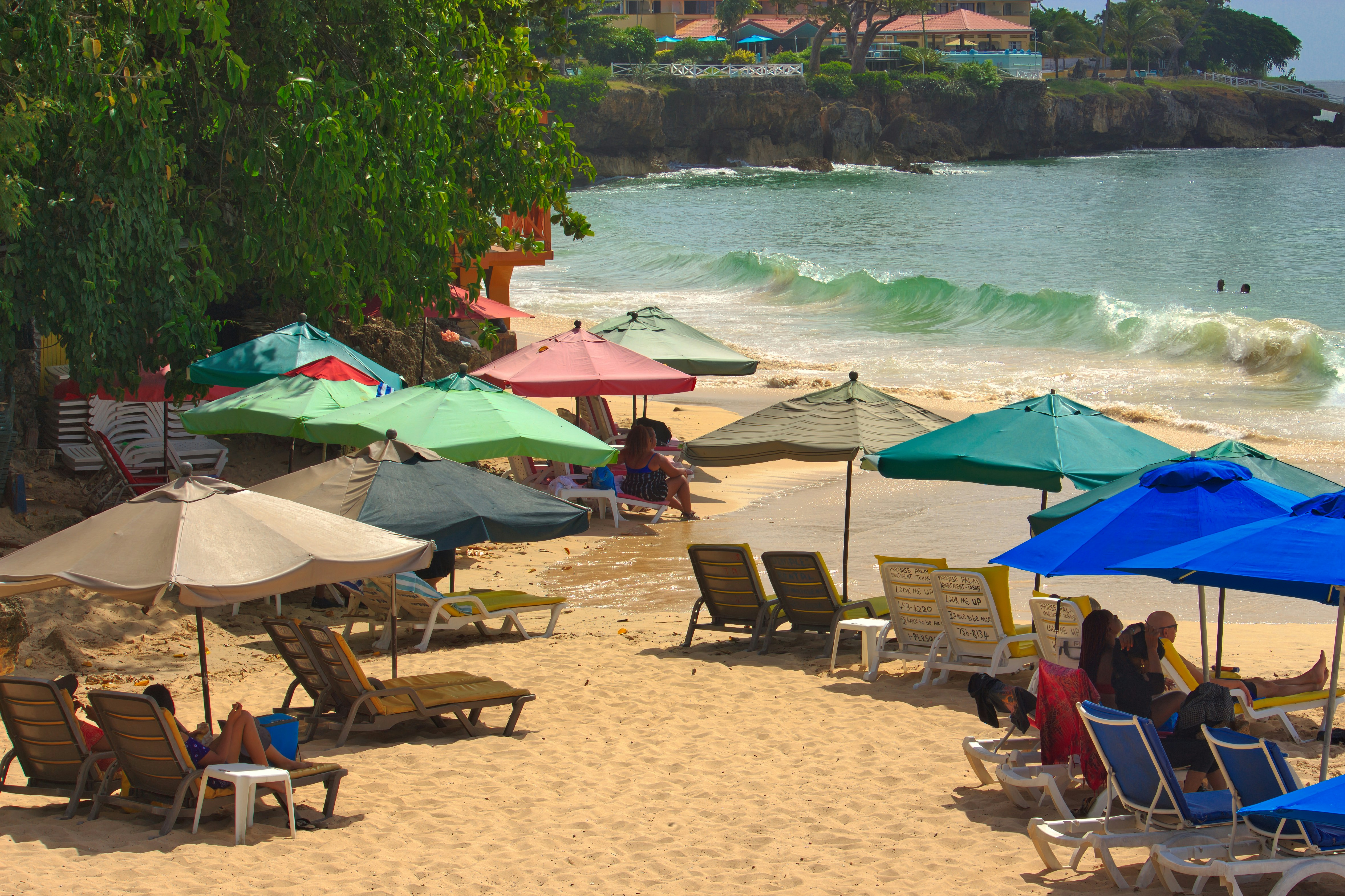Sandy beach with colorful umbrellas, lounge chairs, and ocean waves