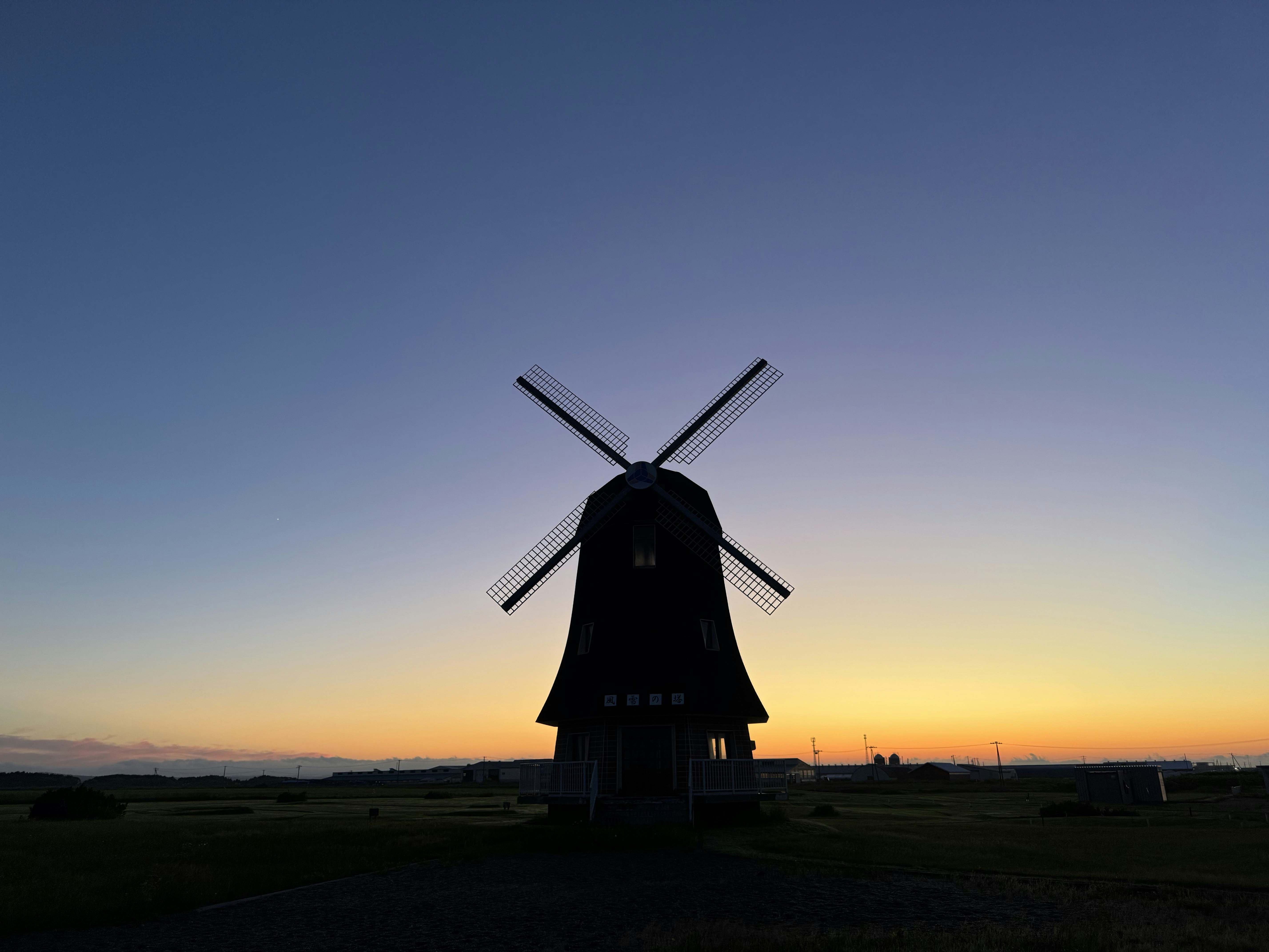 A windmill silhouetted against a colorful sunset sky