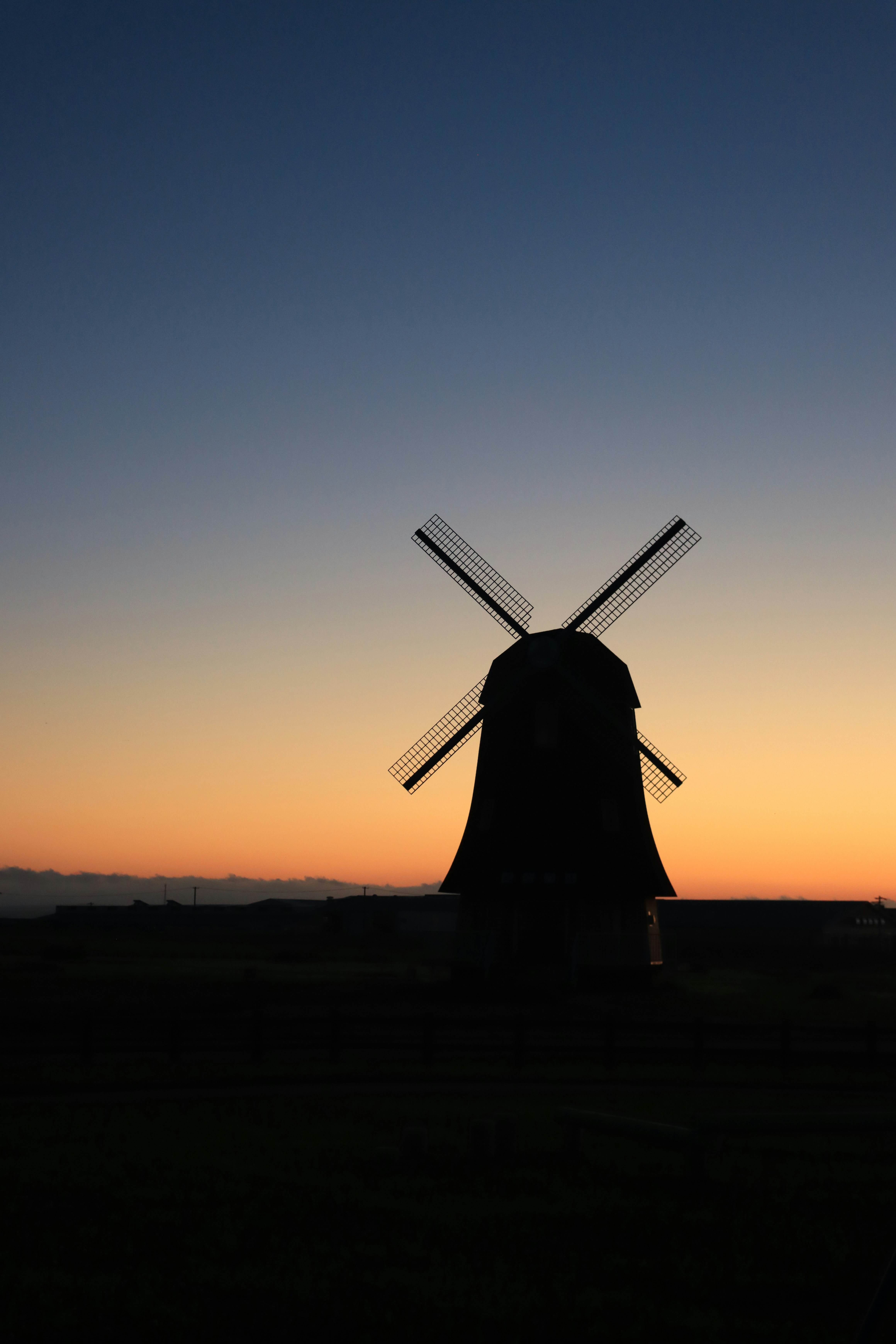 Windmill silhouette against a vibrant sunset sky