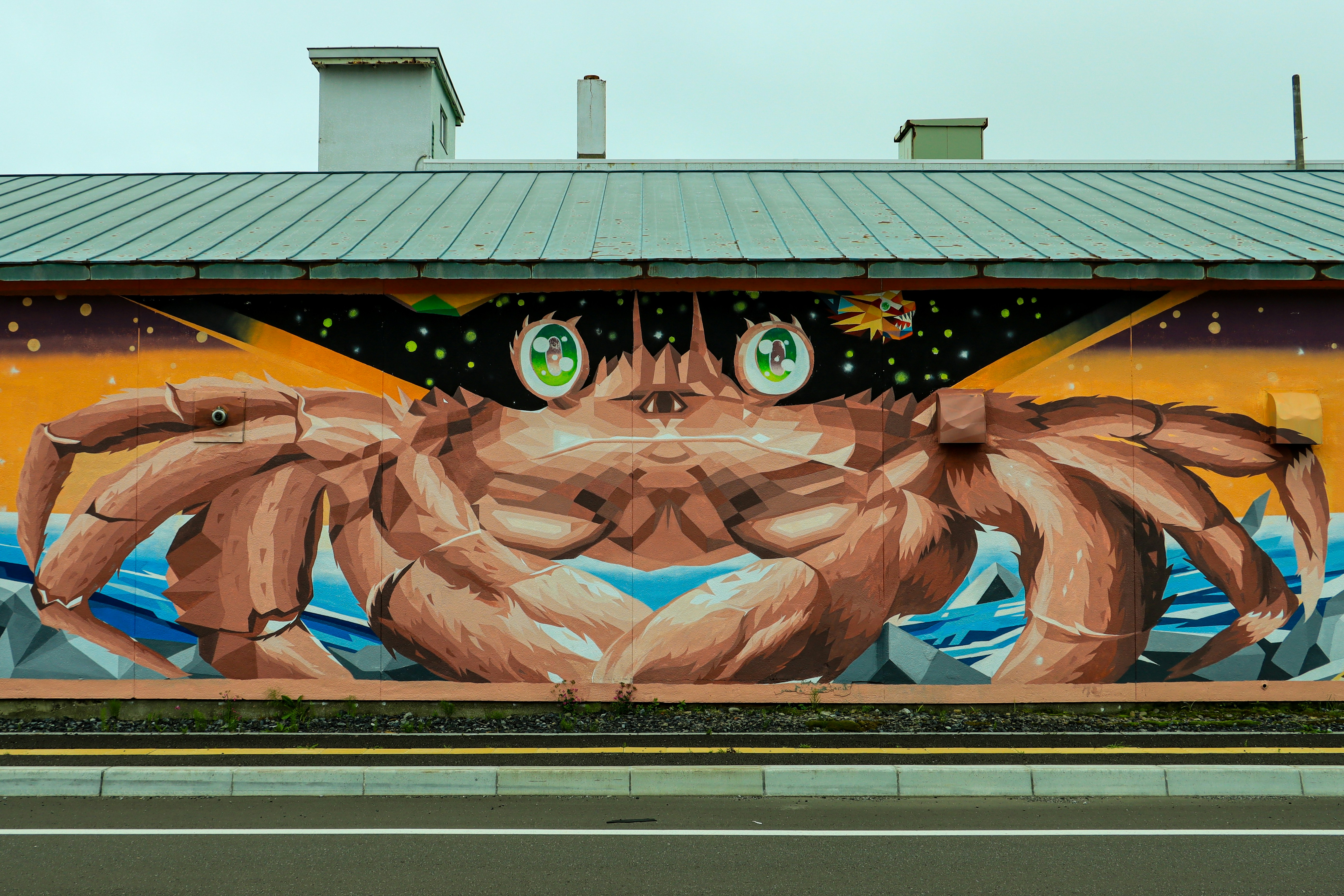 Mural of a large brown crab with green anime eyes