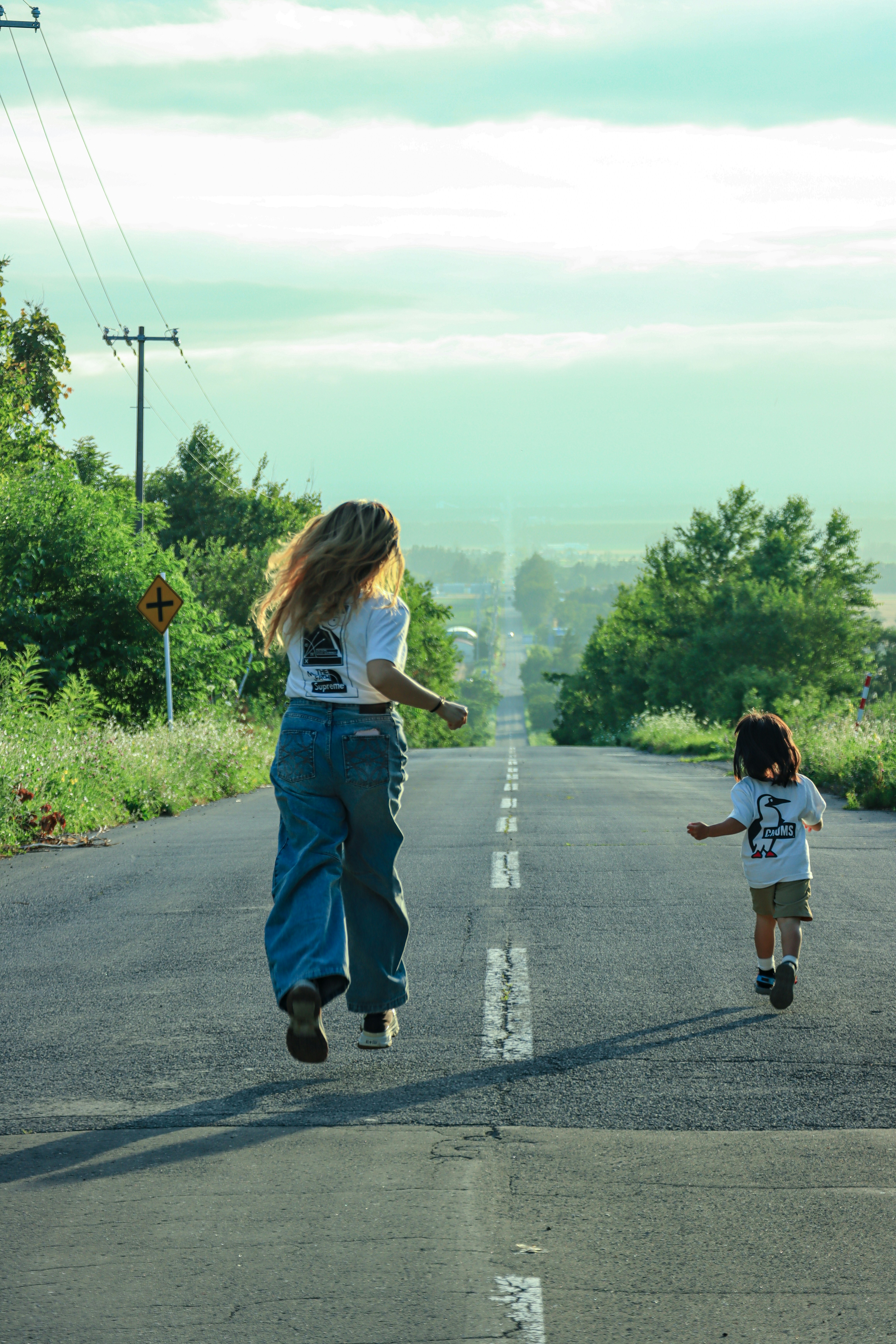 Woman and child running on an empty country road