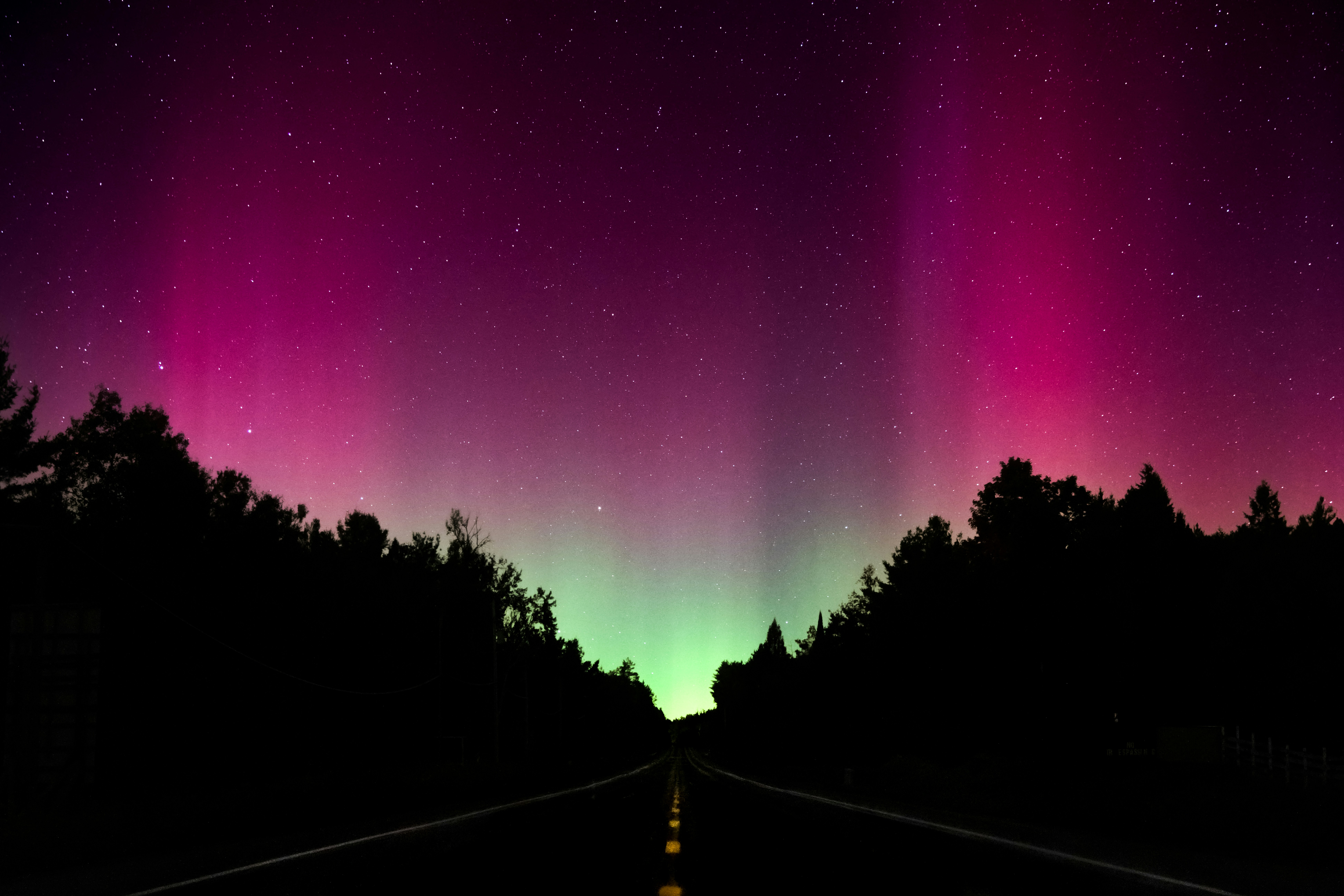 Nordlichter erhellen den Nachthimmel über einer dunklen Straße
