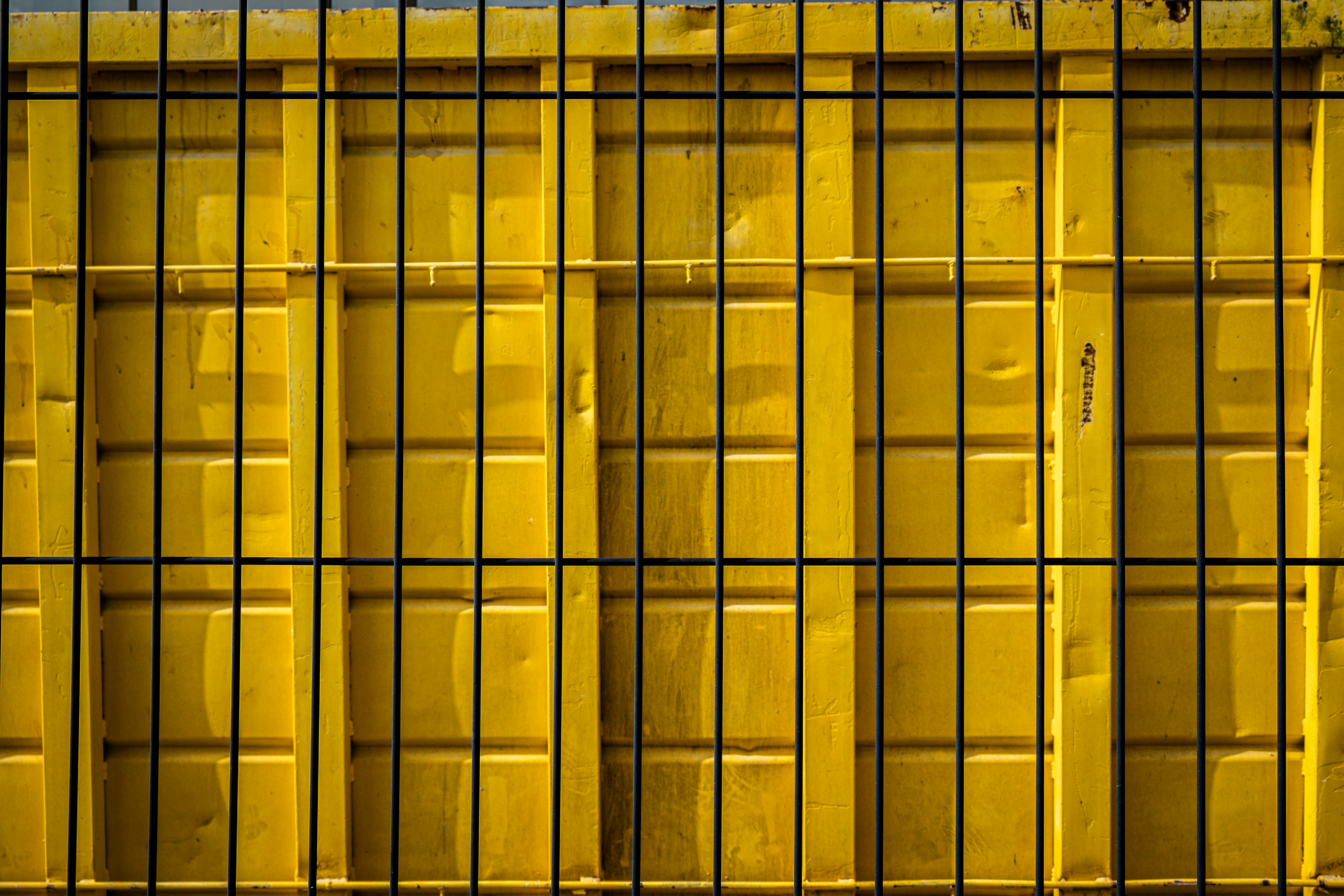 A bright yellow corrugated metal wall with dark bars.