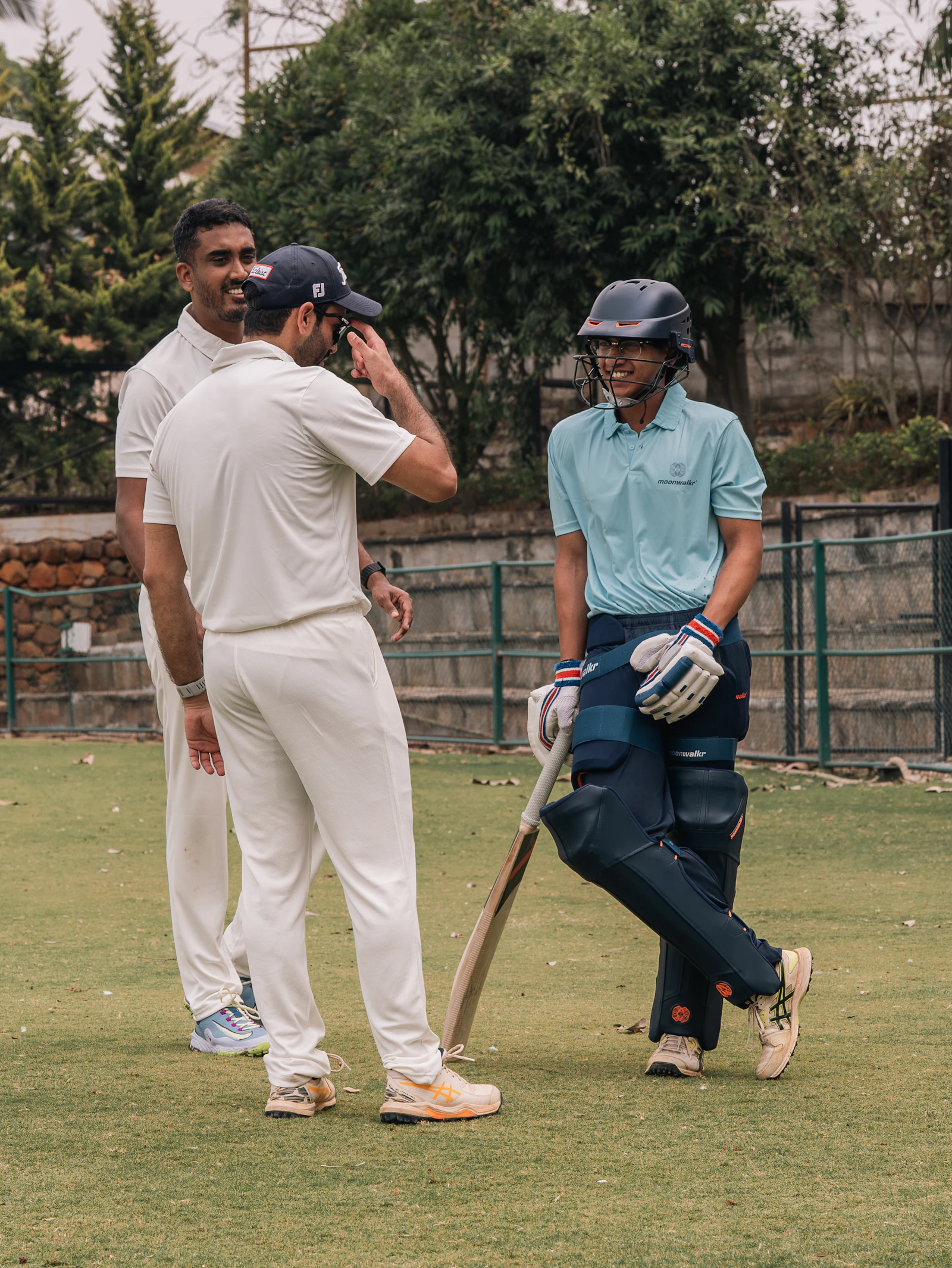 Two cricketers chatting and smiling on a sunny green field