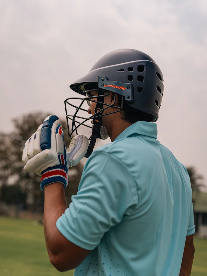 Cricketer in helmet wearing batting gloves