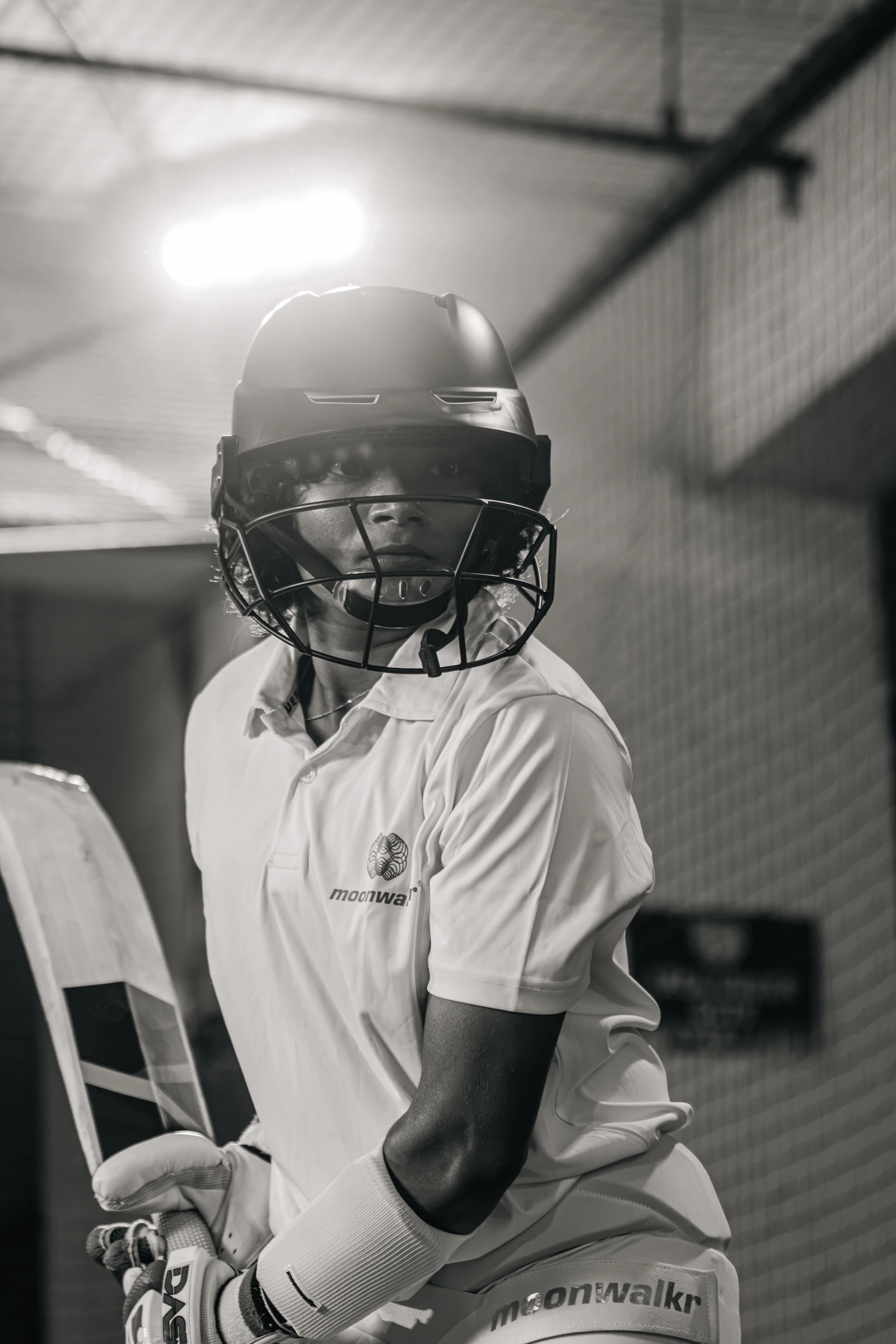 Young cricketer wearing a helmet holding a bat indoors