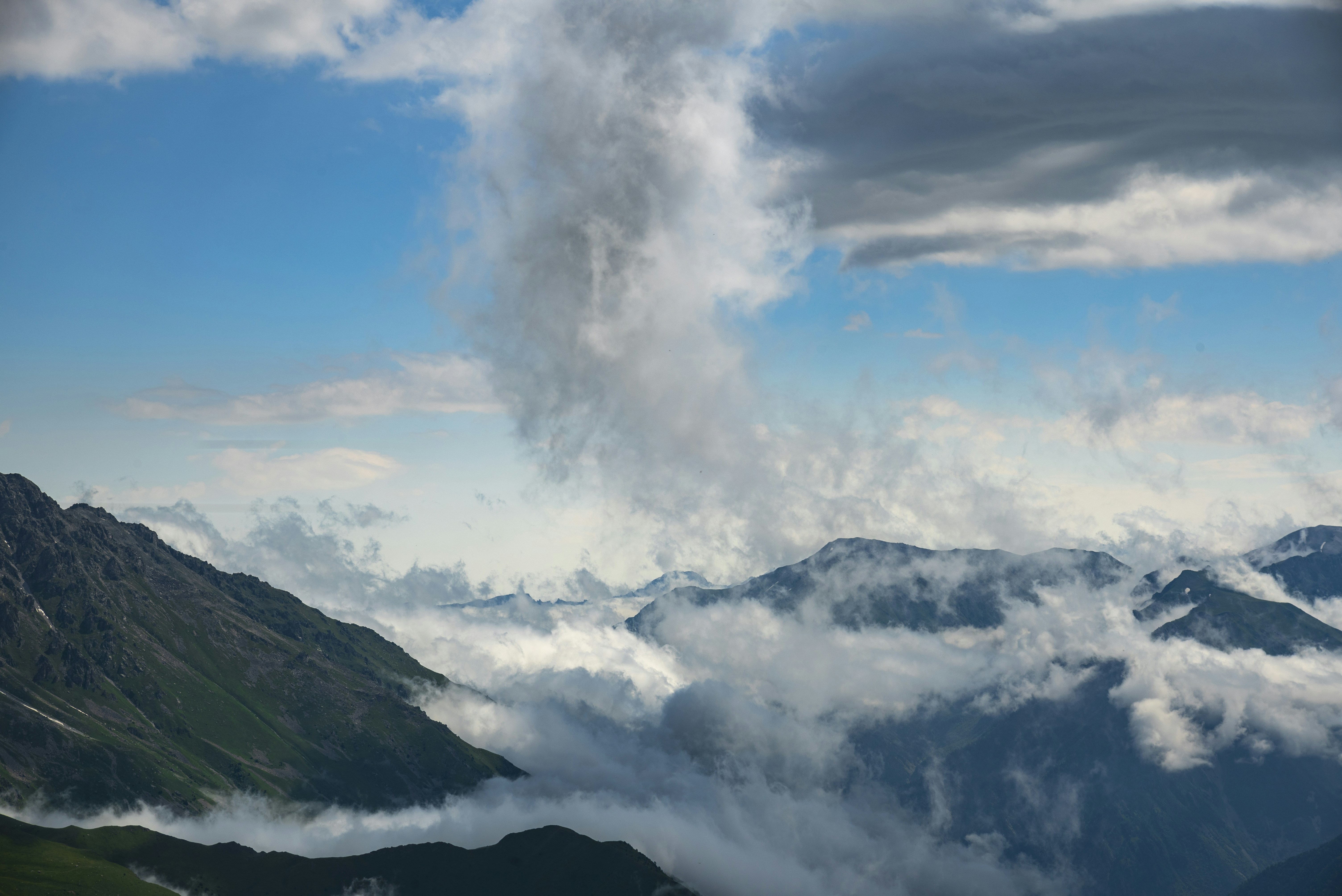 Des nuages spectaculaires se forment au-dessus des sommets verdoyants de montagnes