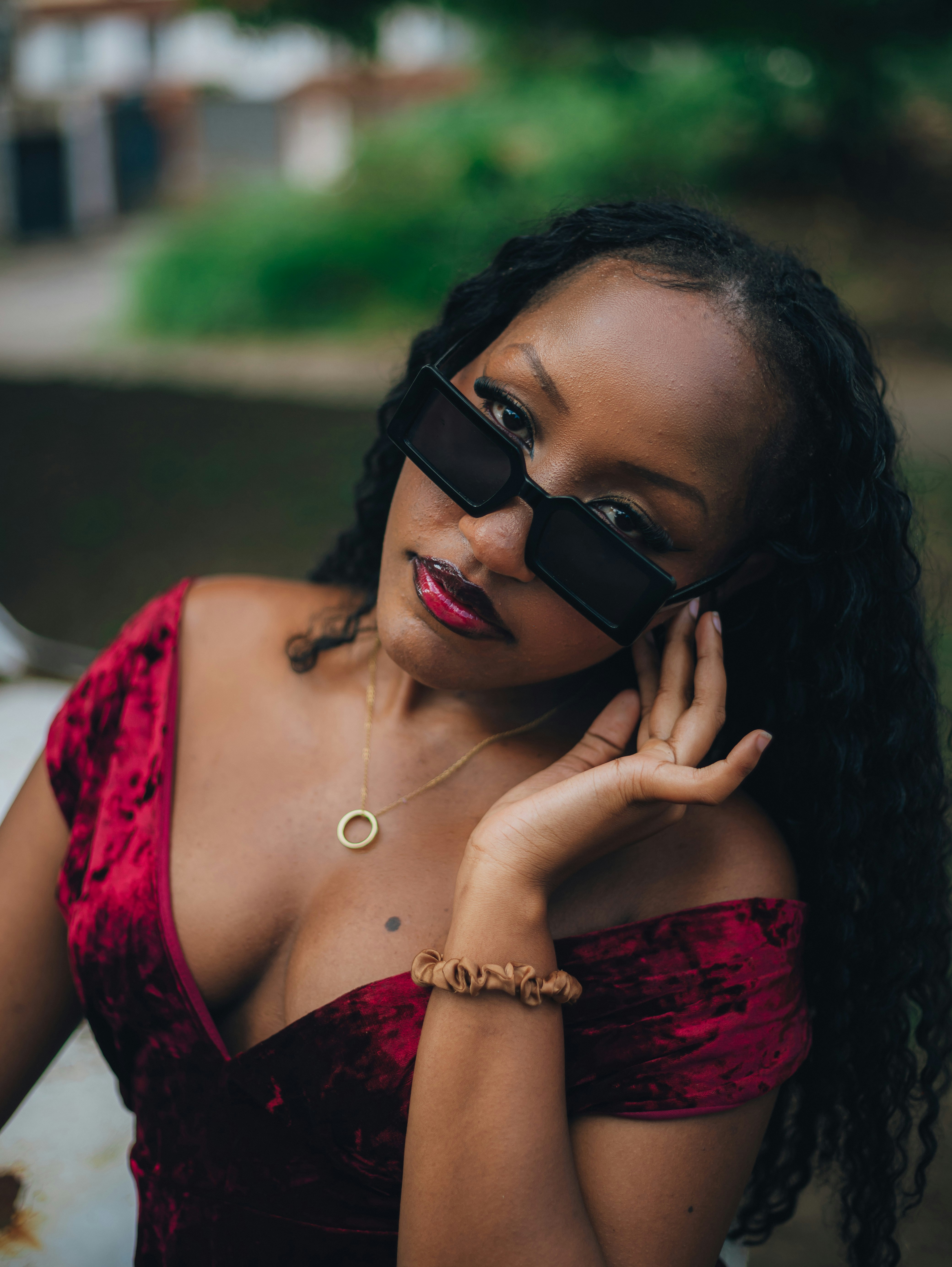 Stylish woman in velvet dress and sunglasses looks at camera.