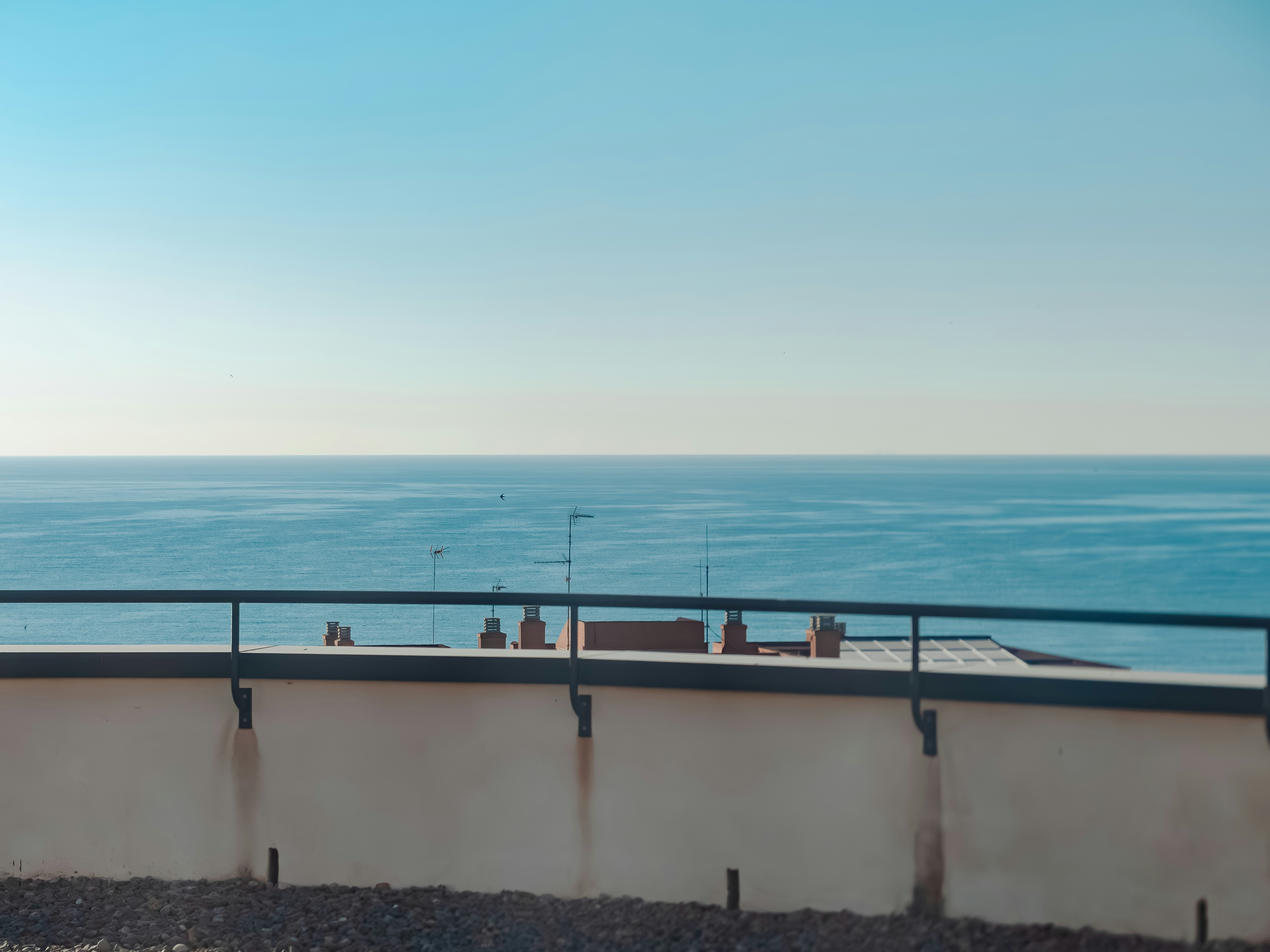 A railing above rooftops and the sea