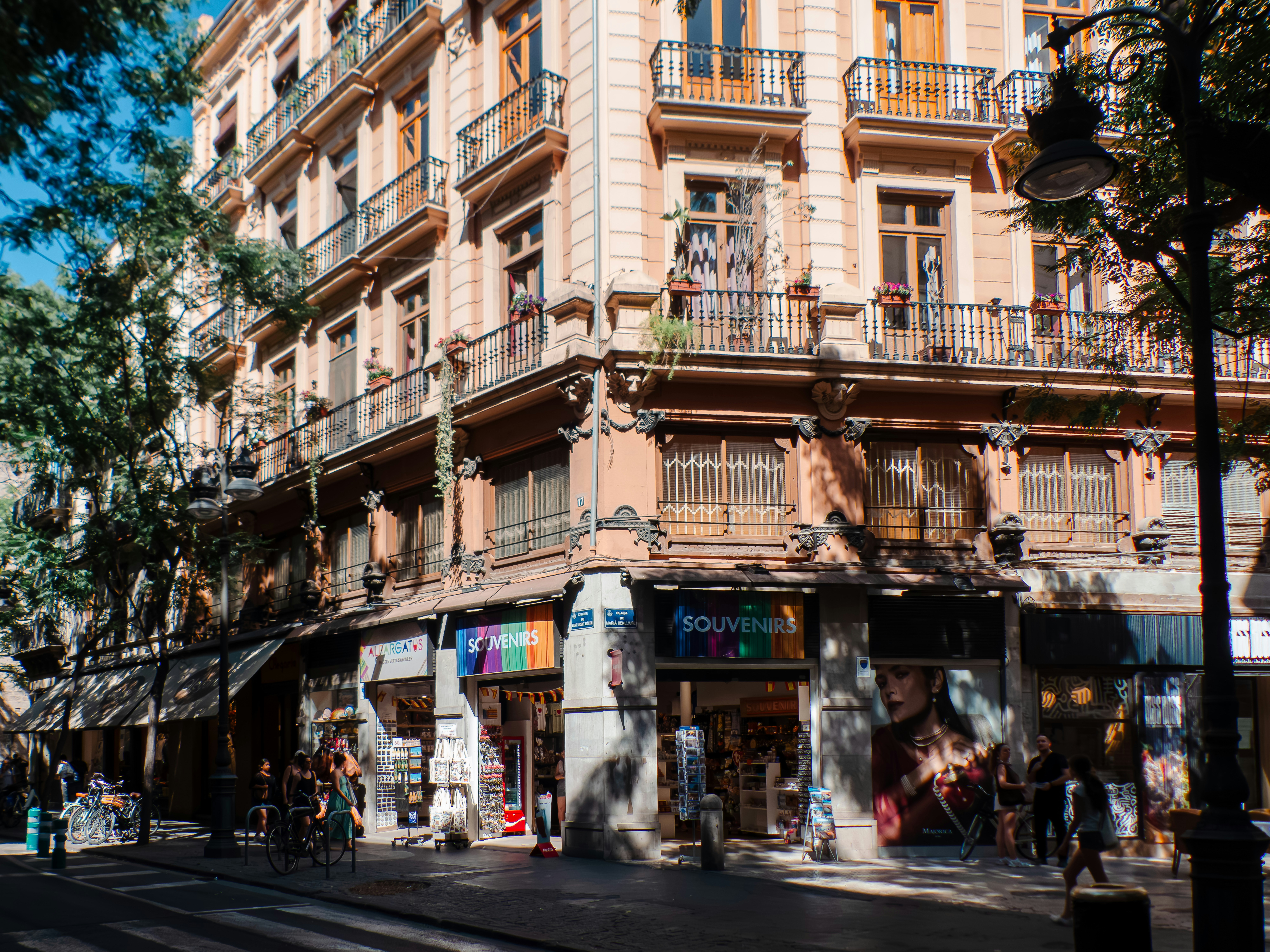 A corner building with balconies above souvenir shops on a sunny city street