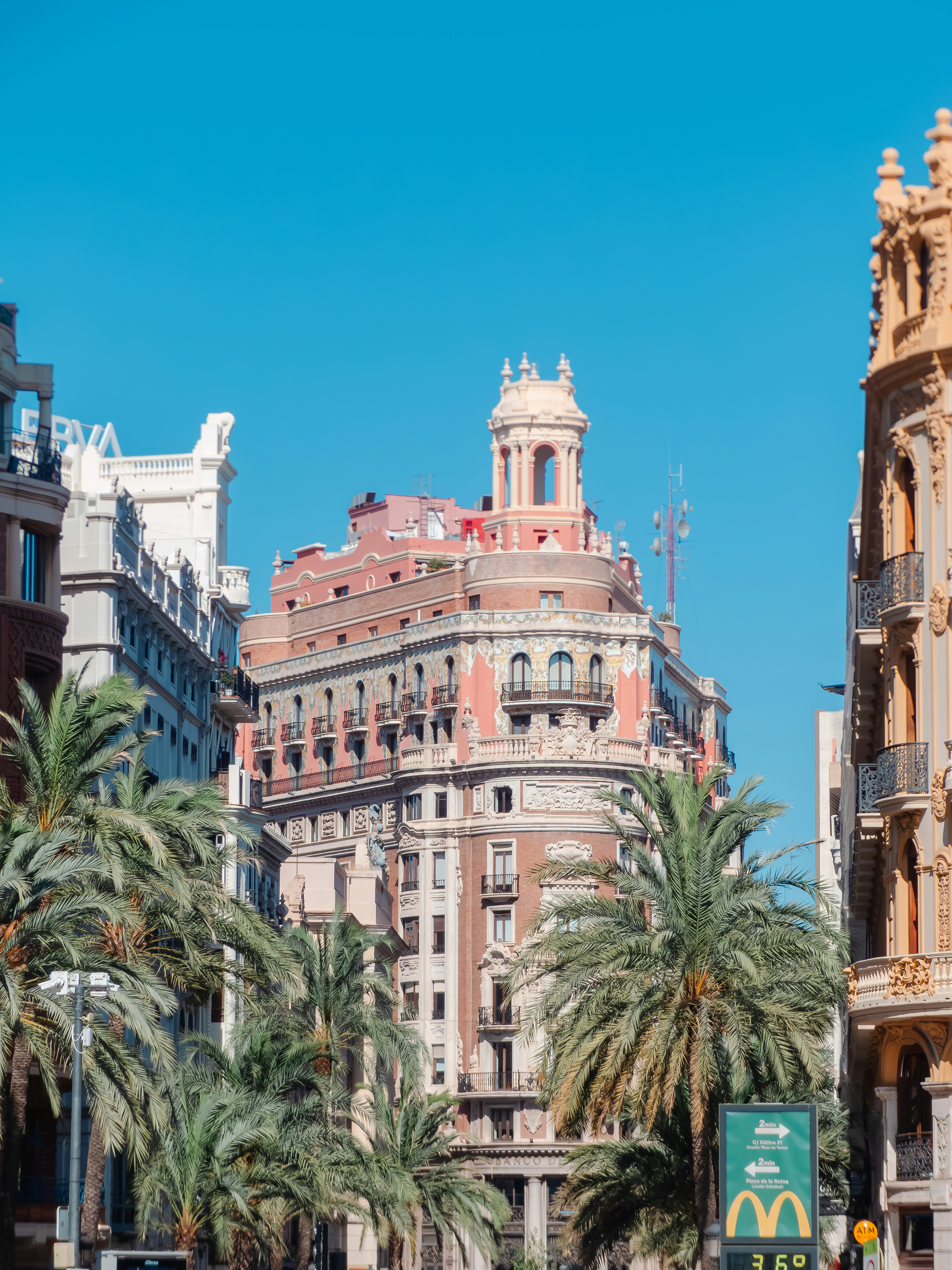 Ornate historic buildings with palm trees under a clear blue sky in Valencia