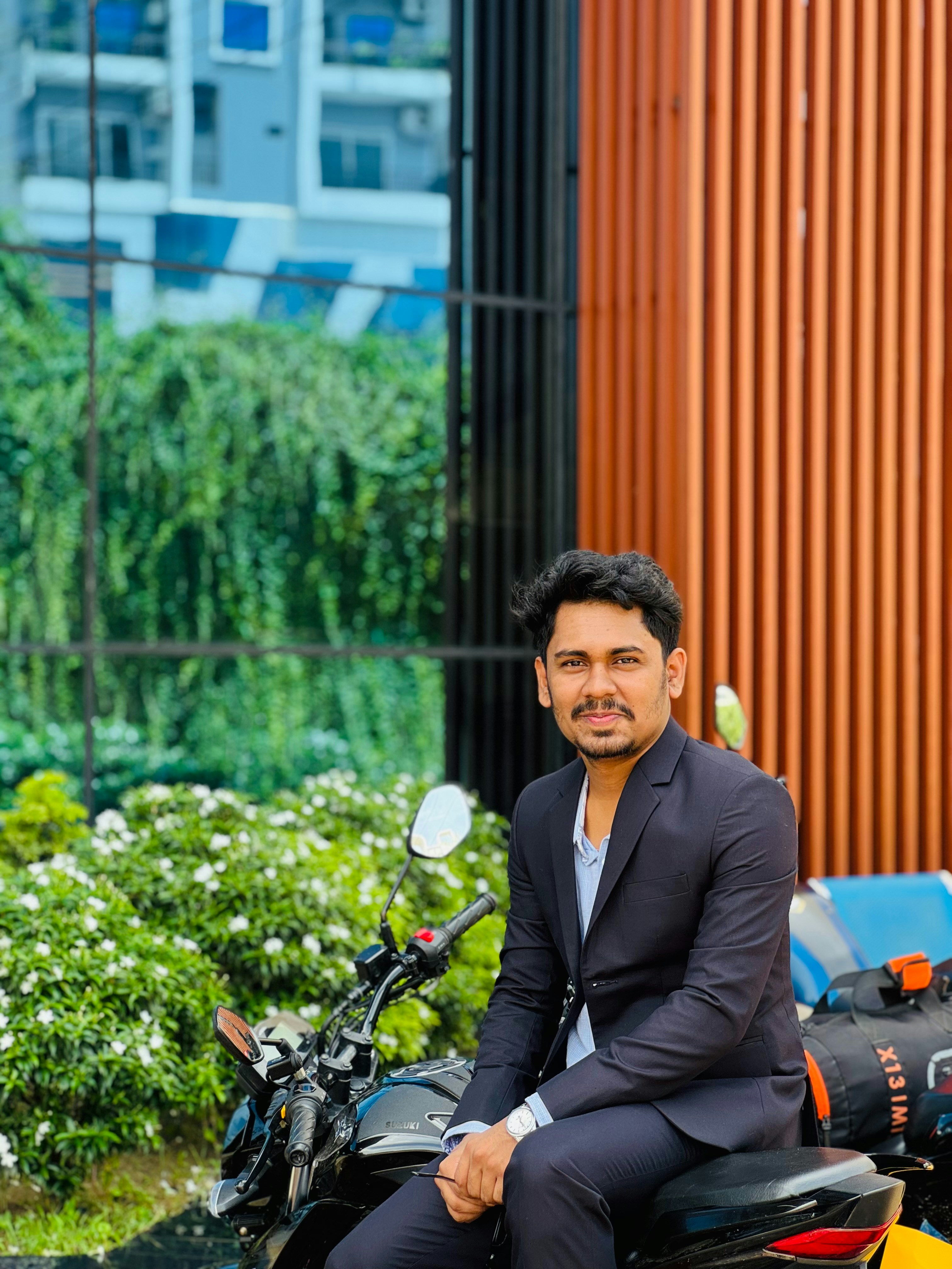 A man in a suit sits on a motorcycle outdoors