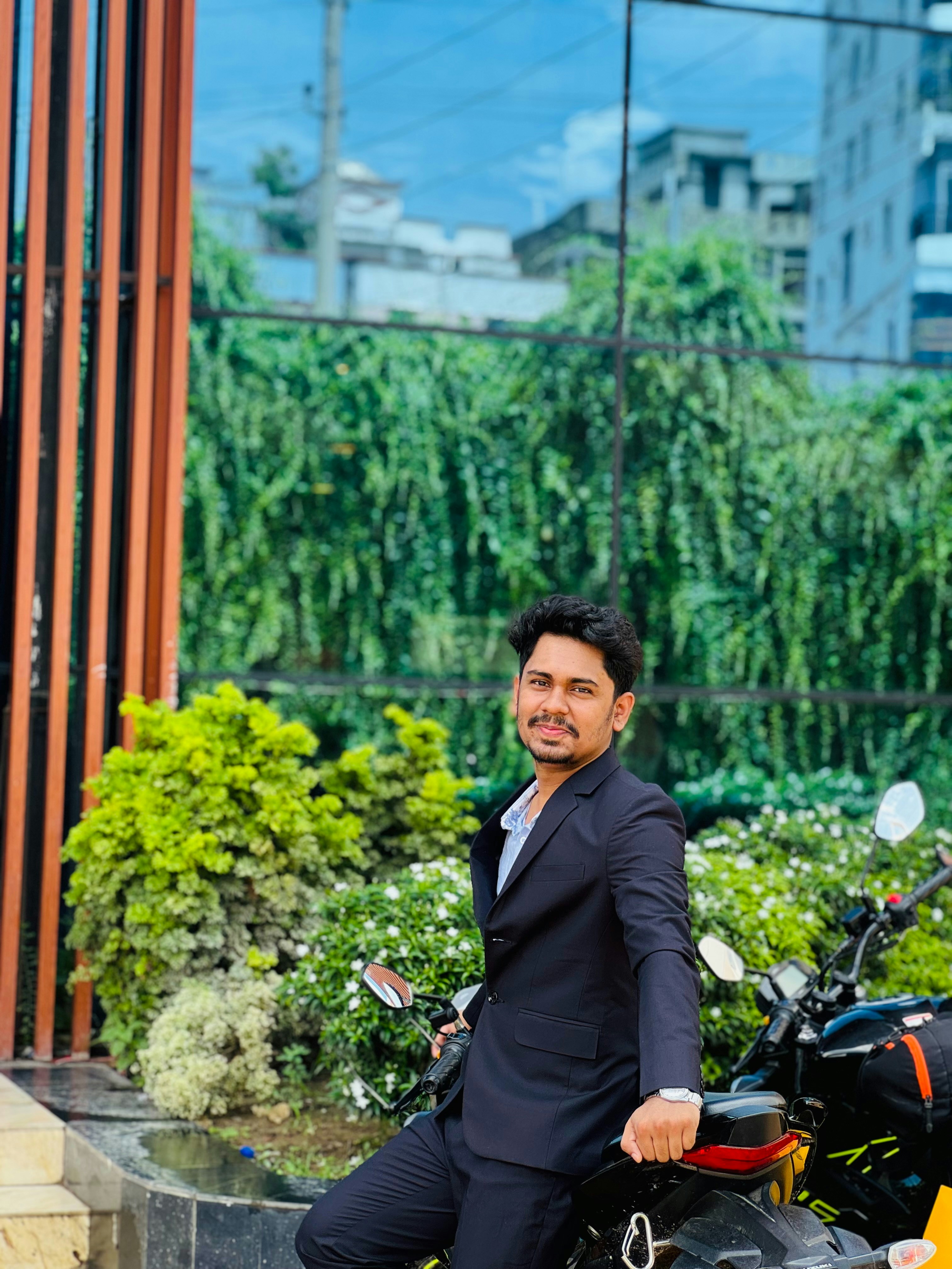 Young man in dark suit poses on motorcycle