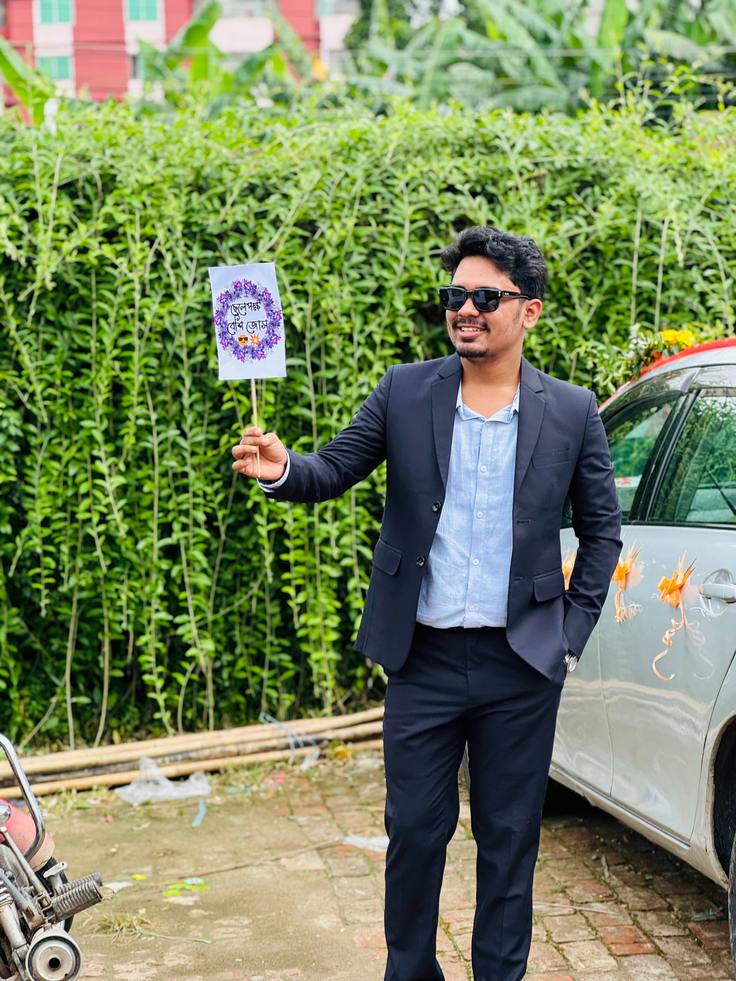 A man in a suit holding a small sign outdoors