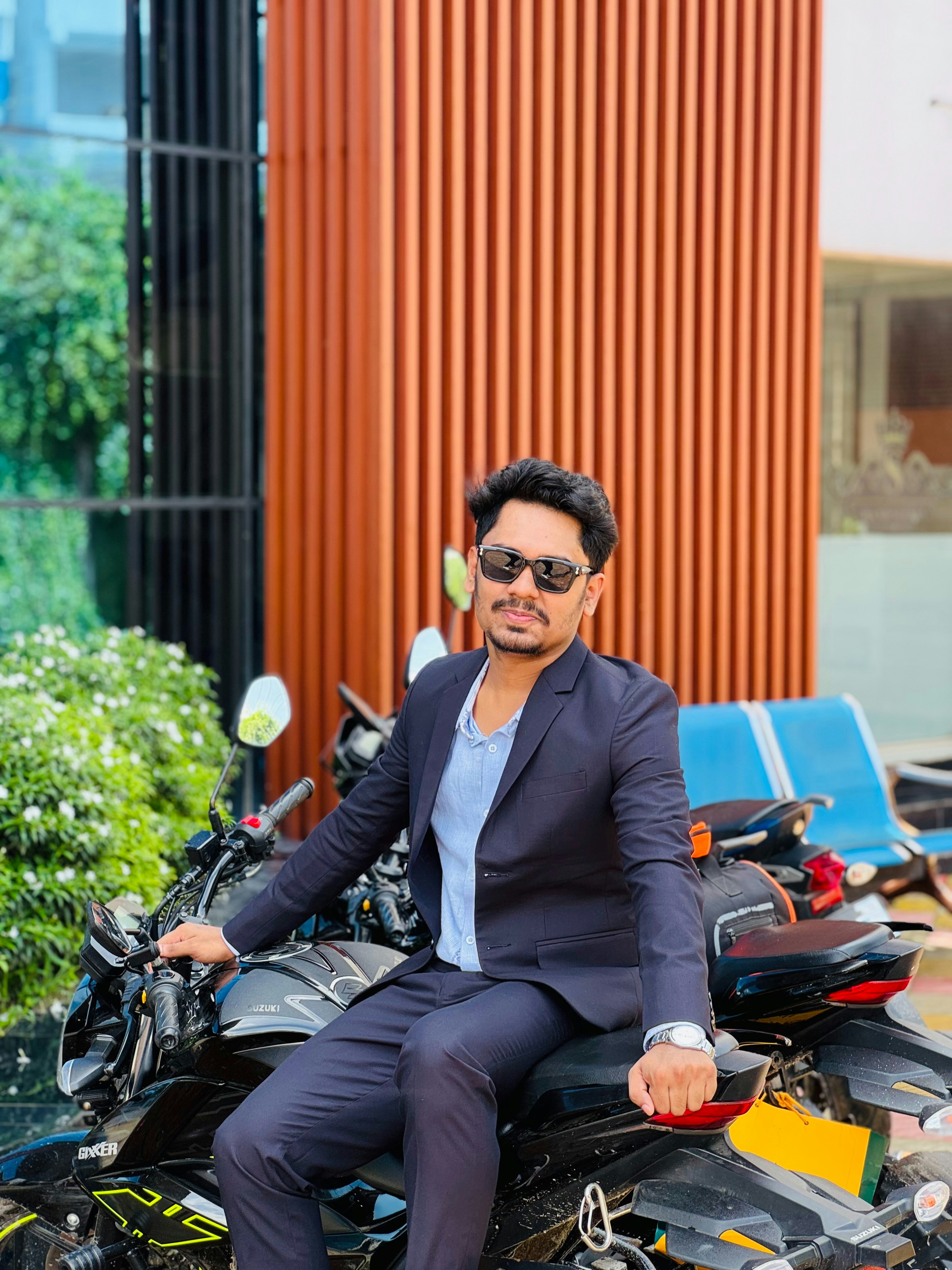 Man in suit and sunglasses on motorcycle outdoors