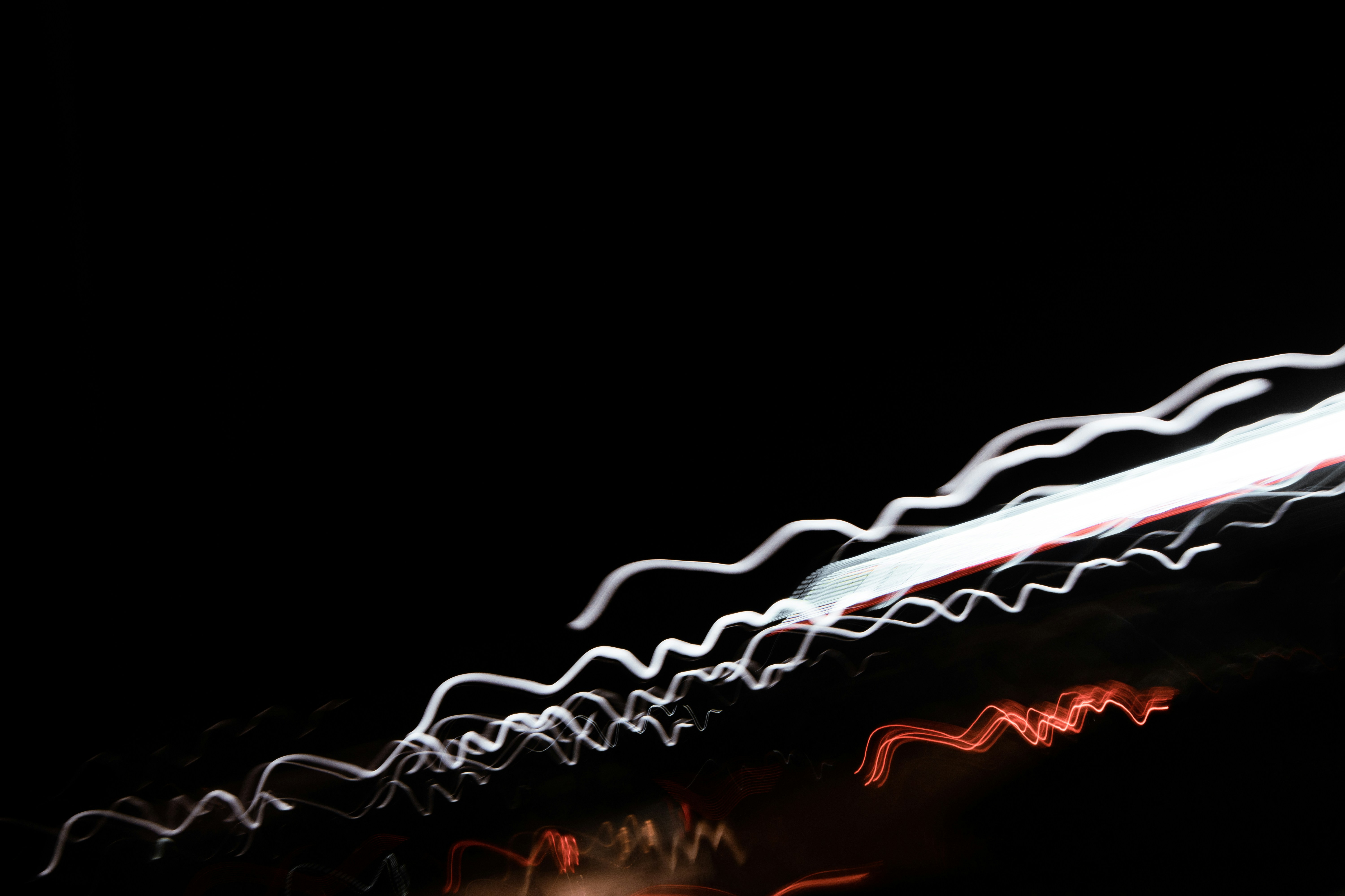 Wavy white and red light trails against a dark background