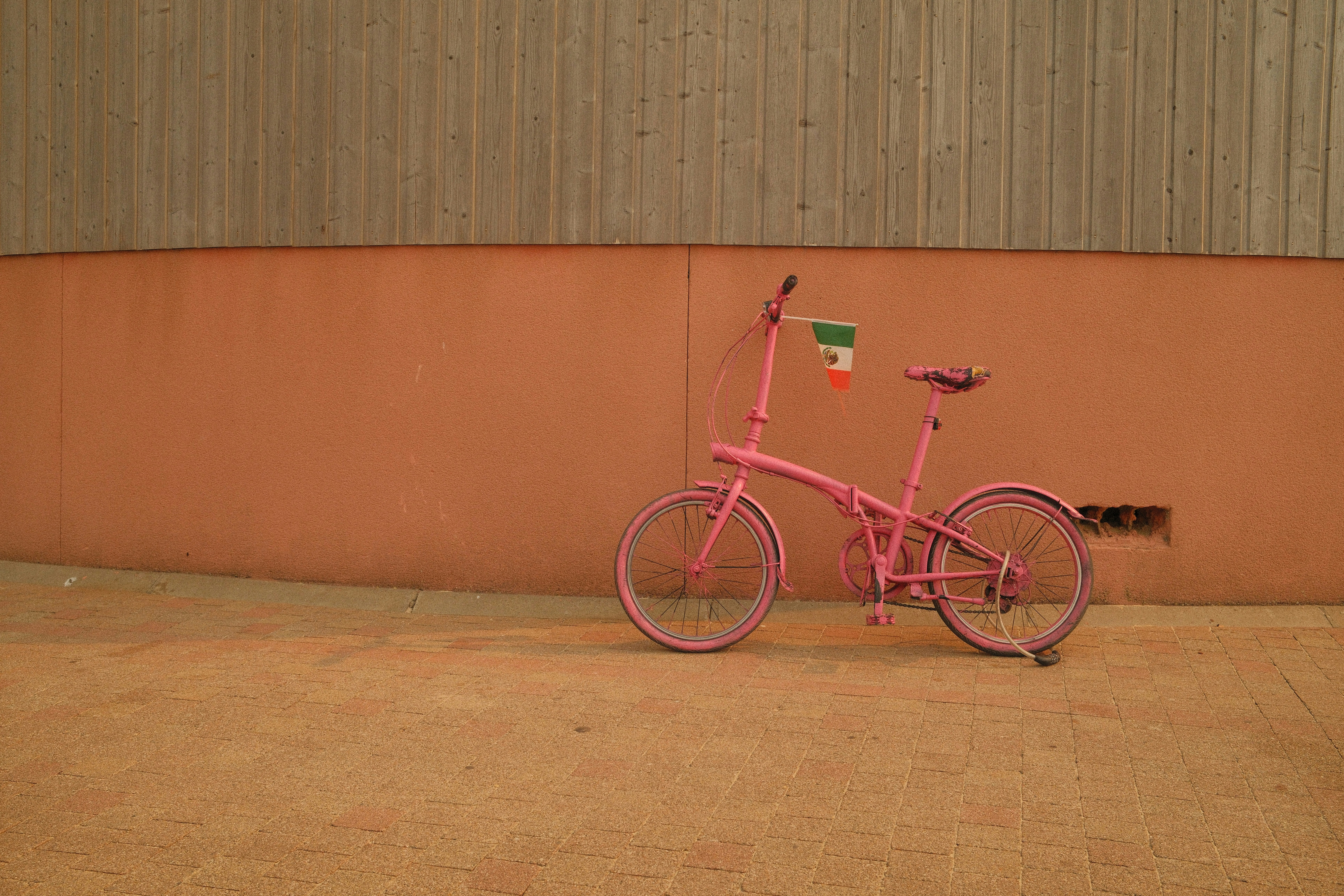 Un vélo pliant rose vif avec un petit drapeau mexicain sur le guidon