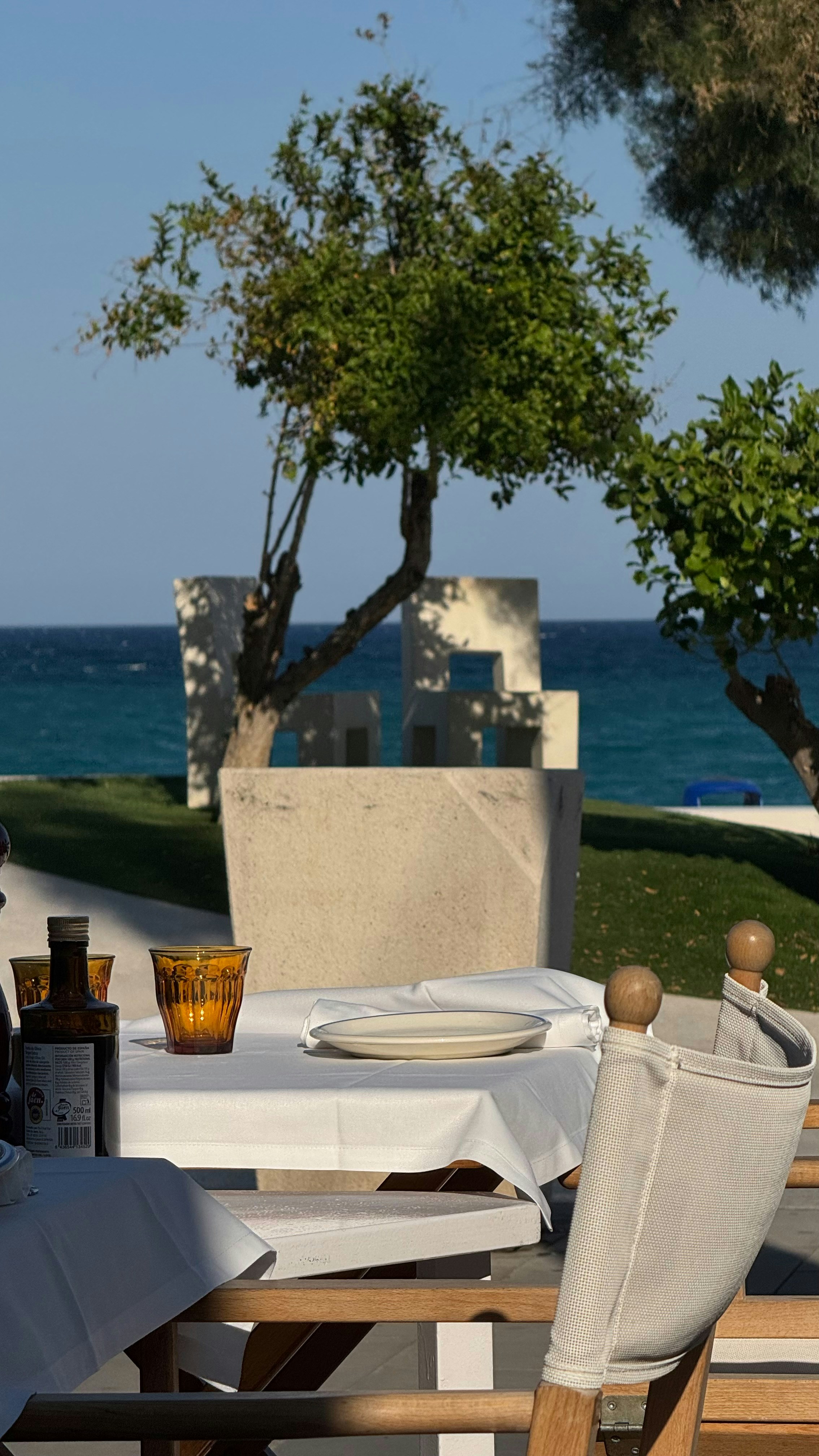 A table set with a white cloth and glassware overlooking the sea