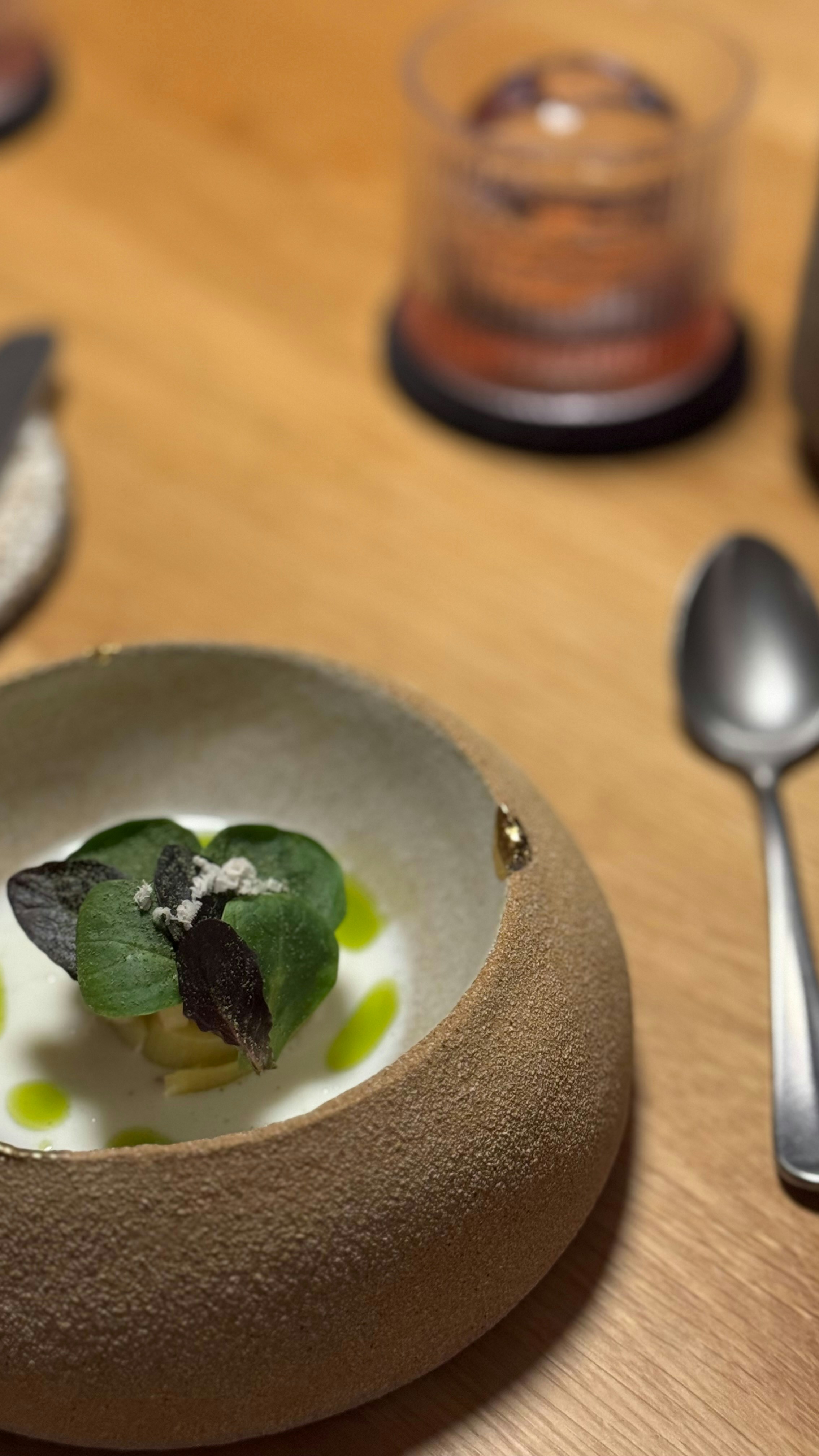 A small portion of food with green leaves in a textured ceramic bowl