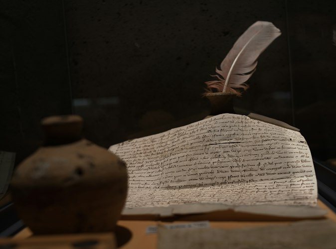 An archivist examining an old photograph and handwritten letter at a work table