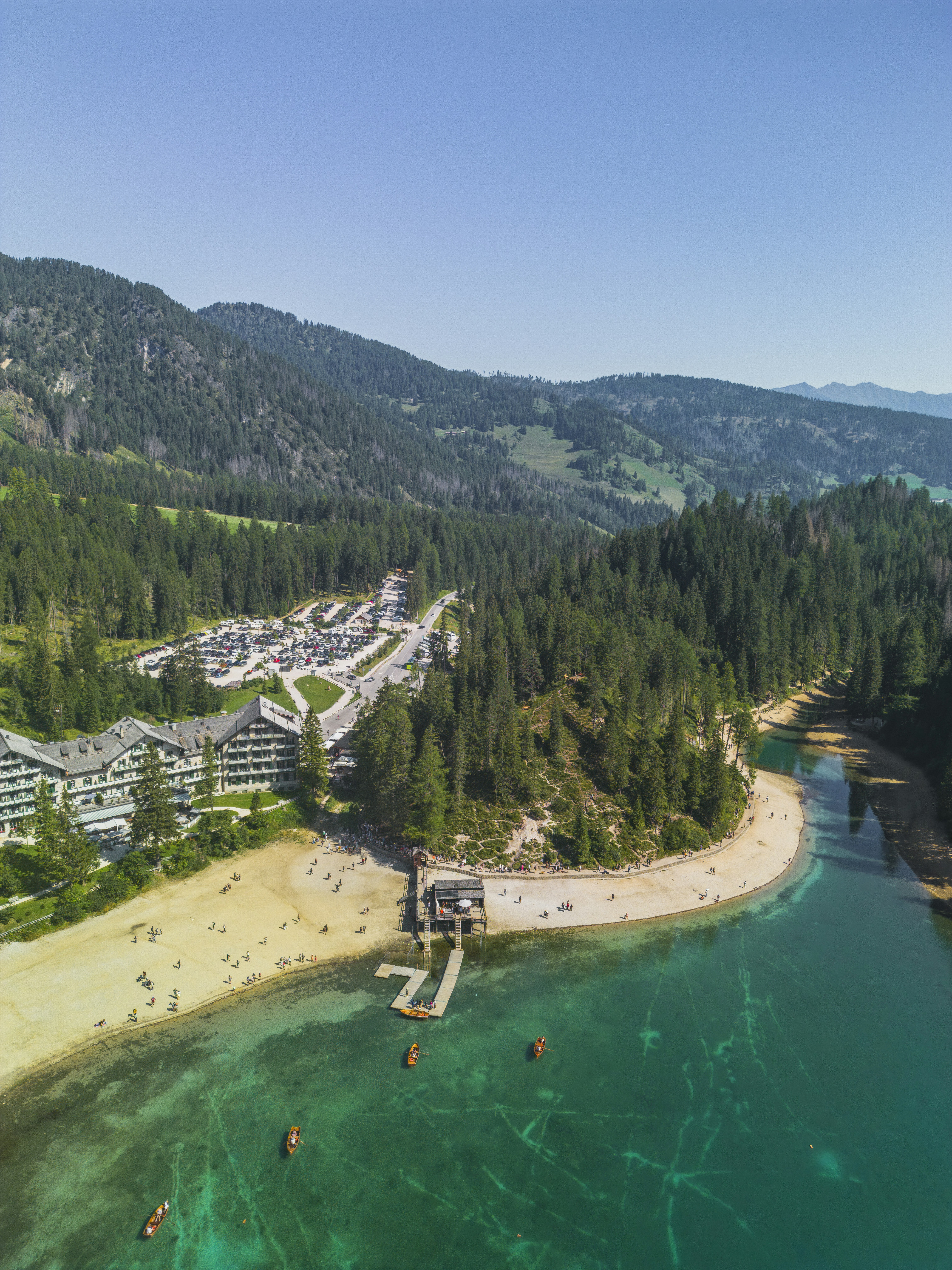 Turquoise lake, sandy beach, and resort nestled in green mountains