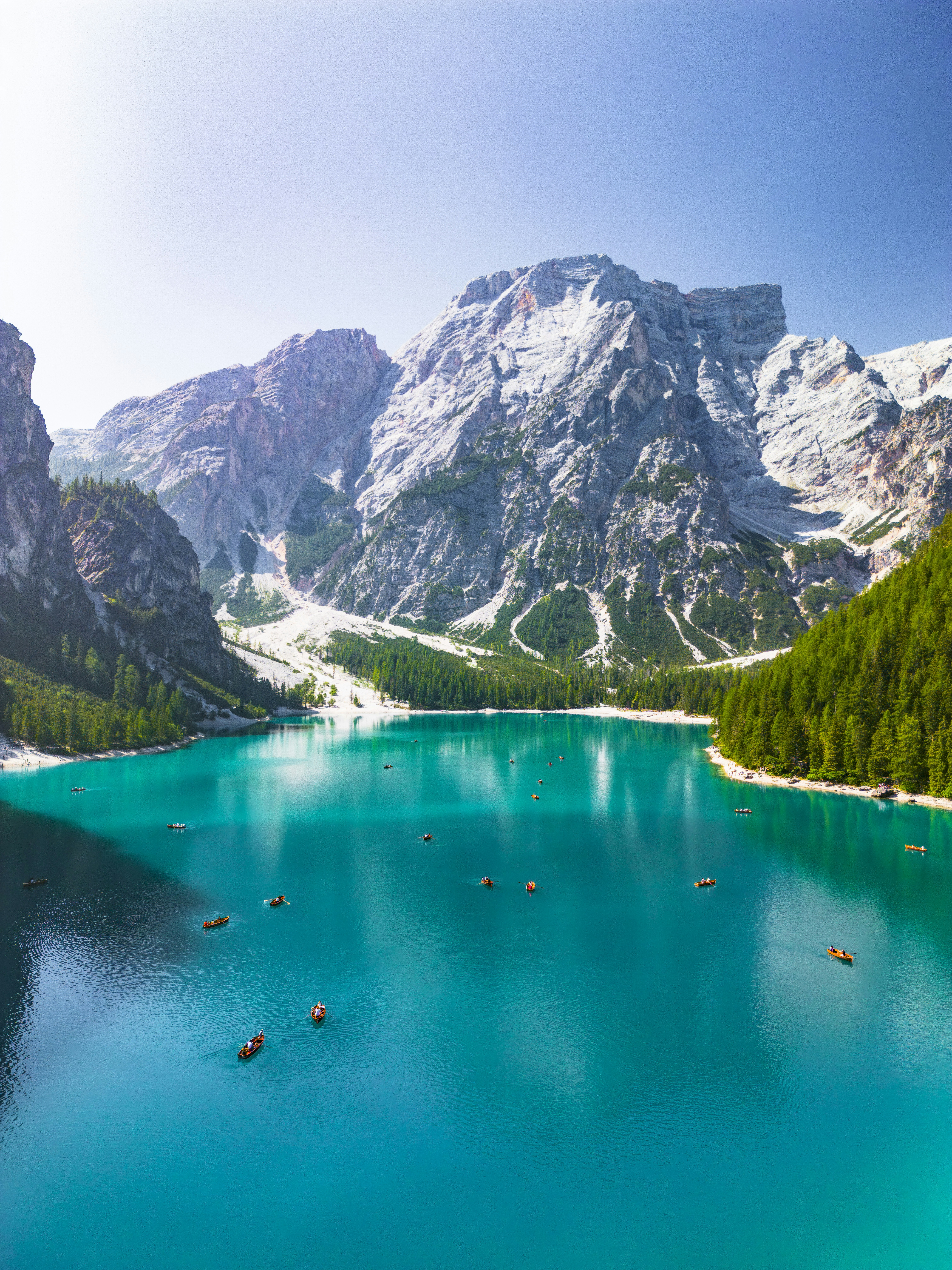 Turquoise mountain lake with boats and lush green forests