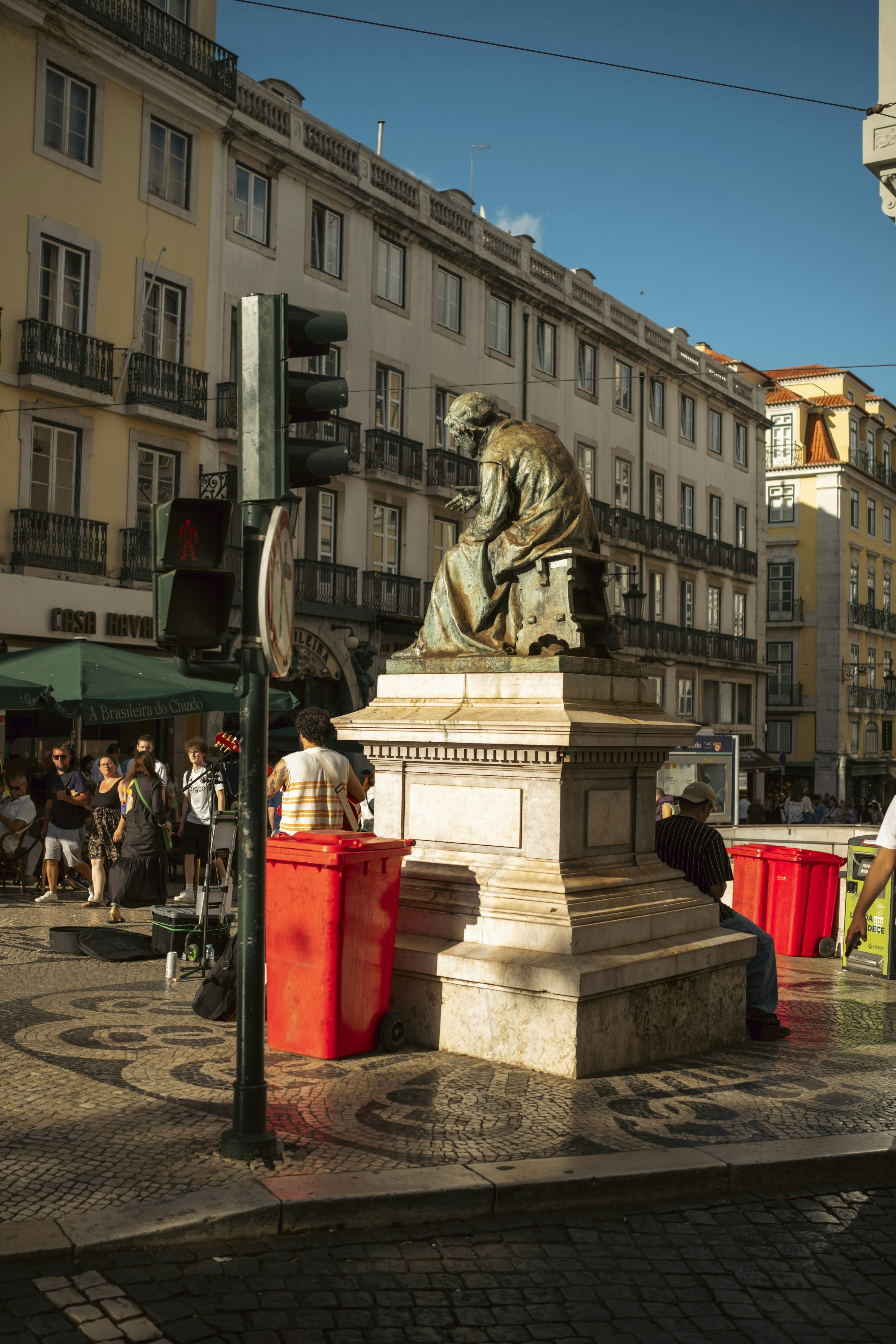 A bronze statue of Fernando Pessoa sitting on a stone pedestal in Lisbon