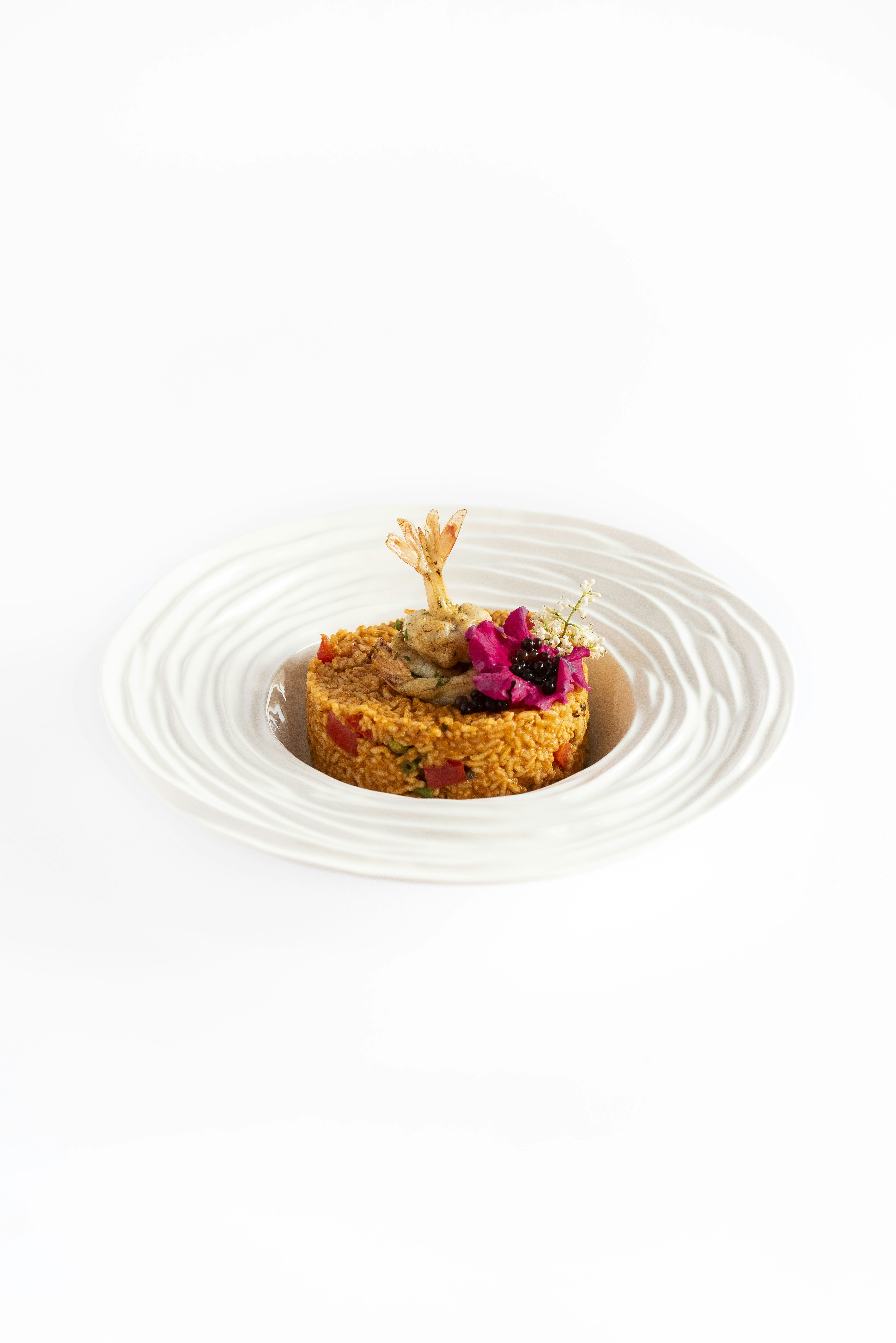 Piatto gourmet salato con gamberi, bacche e fiori commestibili.