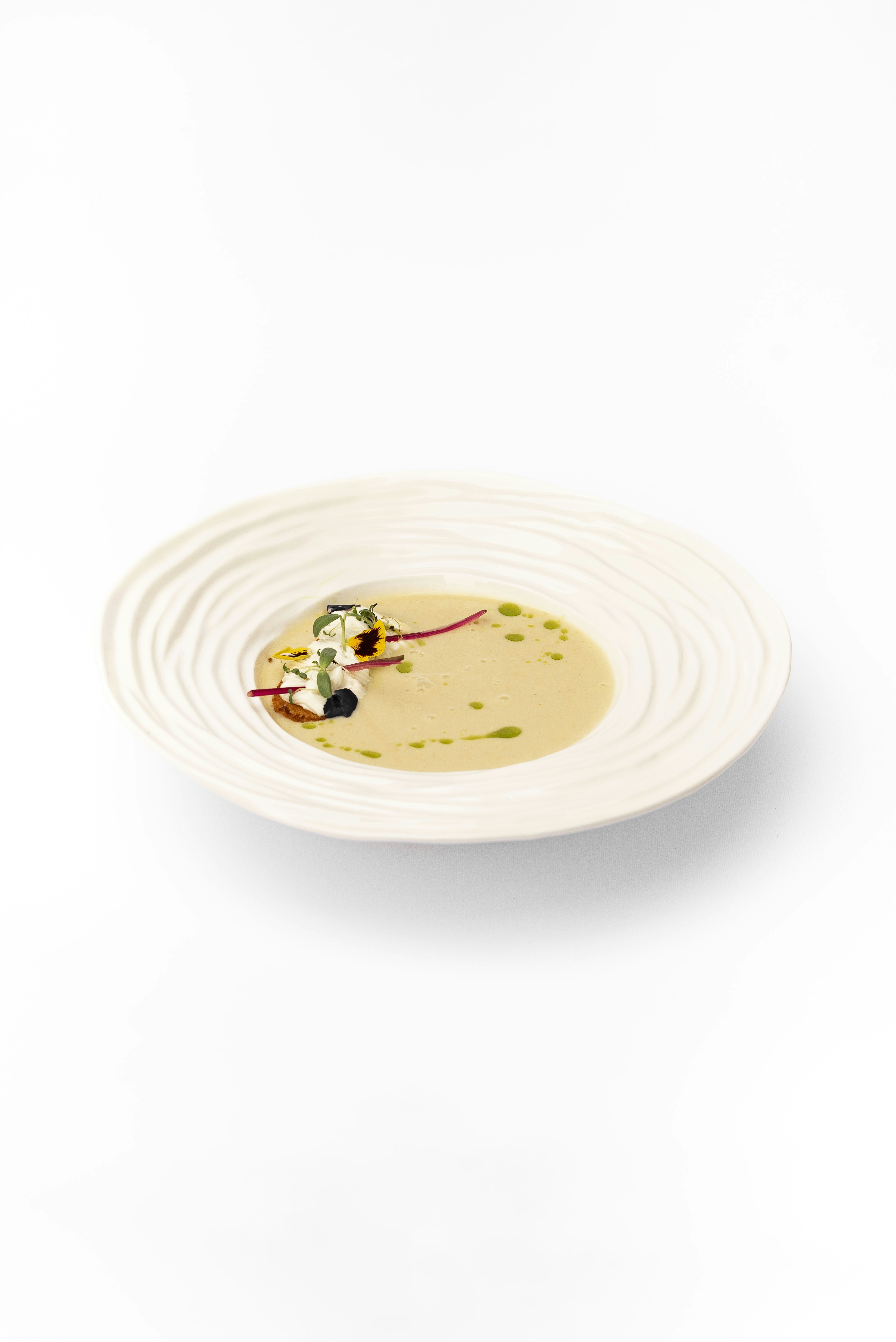 Zuppa alla crema in una ciotola bianca con elegante guarnizione.
