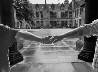 Two people holding hands in front of a historic stone building