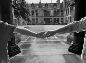 Two people holding hands in front of a historic stone building