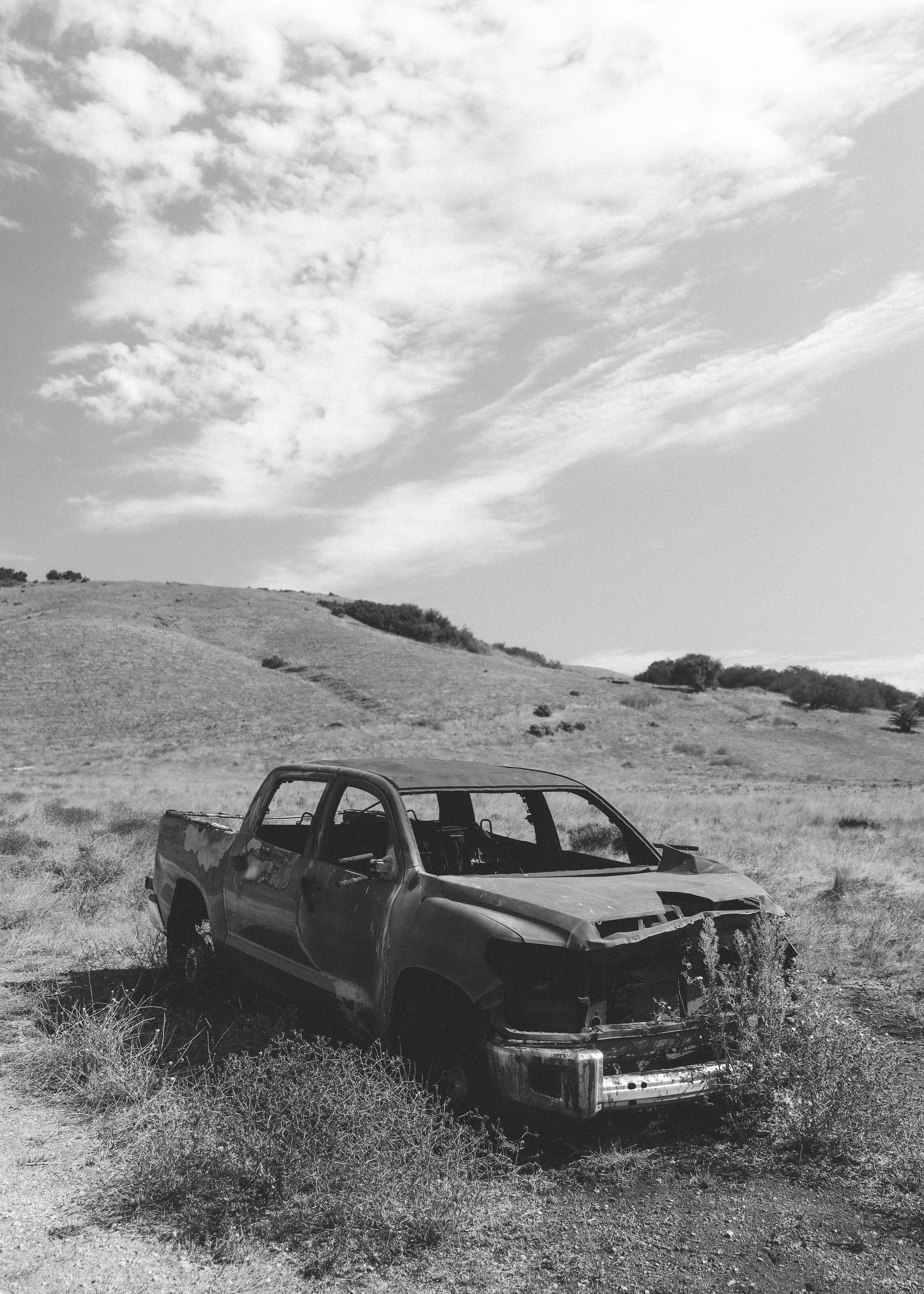 Camión oxidado abandonado en un paisaje seco y montañoso.