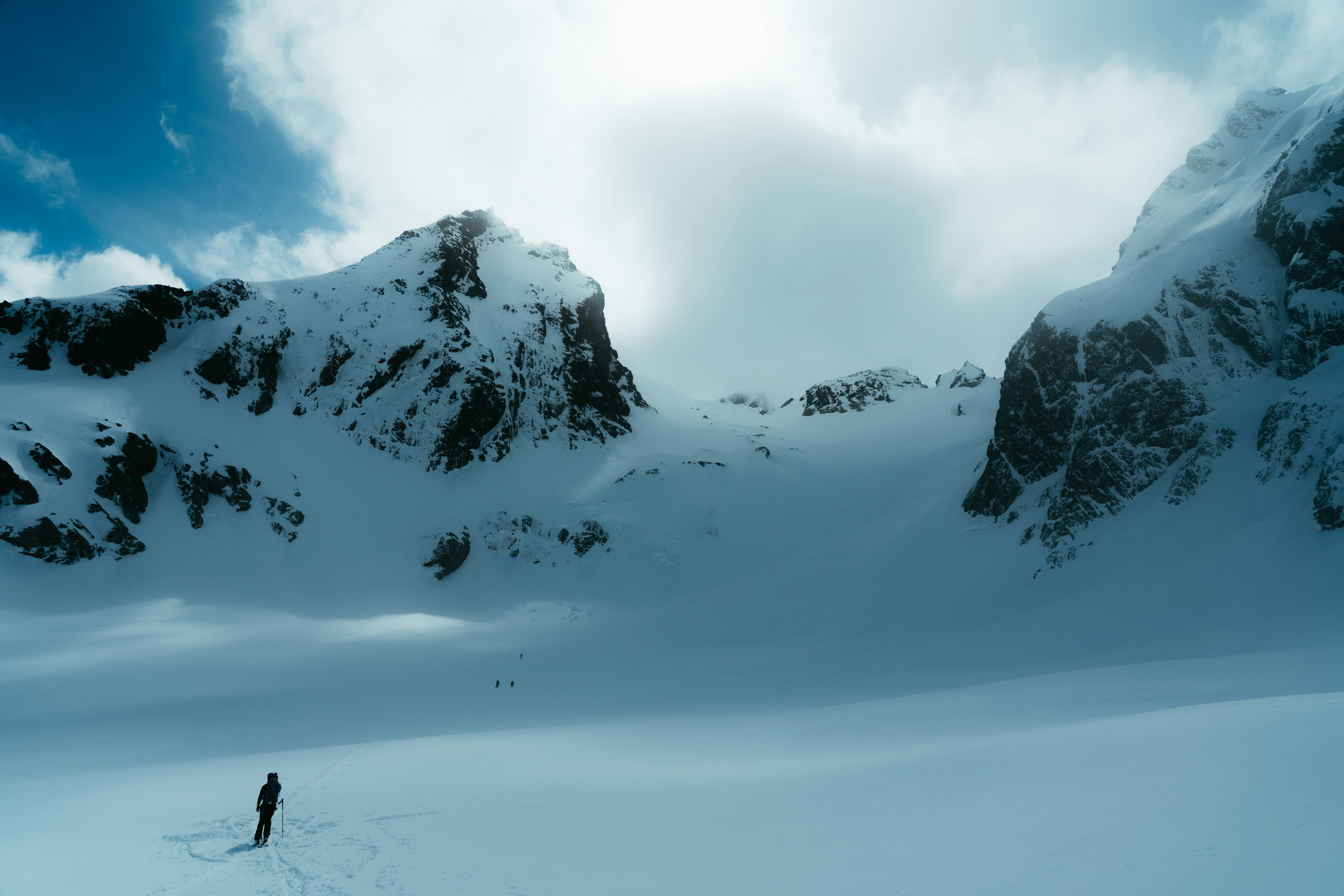 Skier in a vast snowy valley surrounded by mountains.