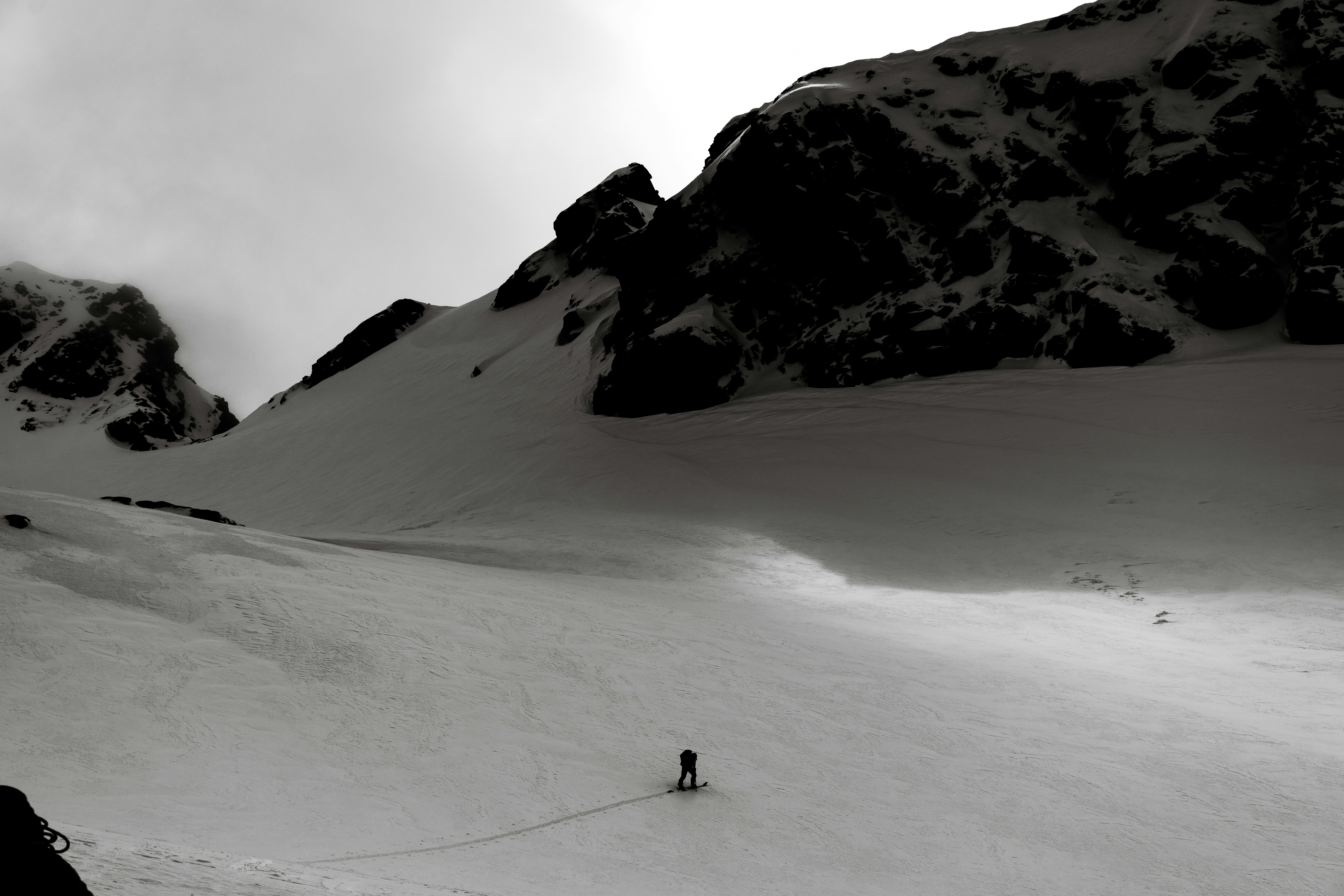 A lone person walks across a vast, snowy mountain landscape.