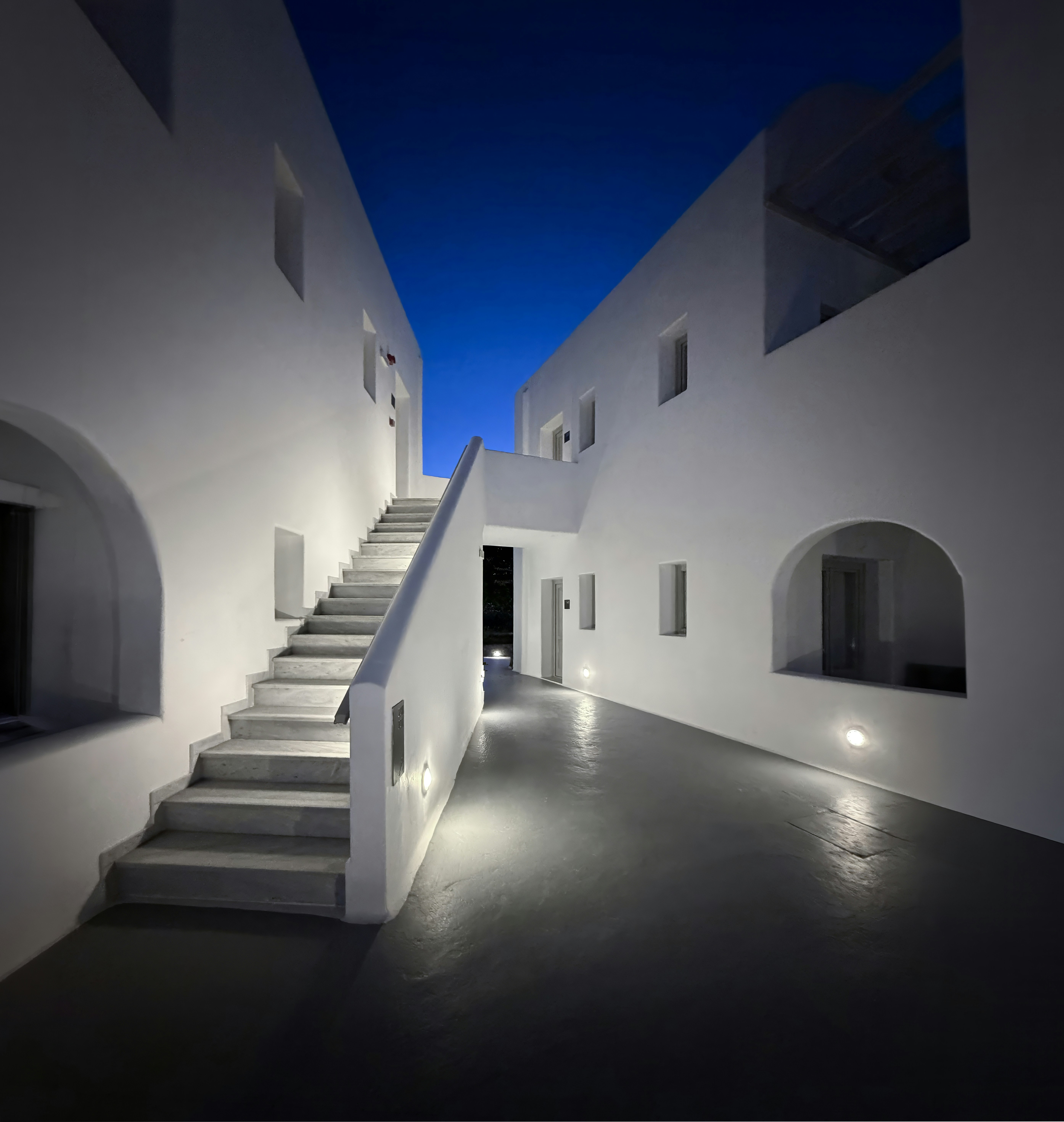 Modern white buildings with illuminated stairs at twilight.