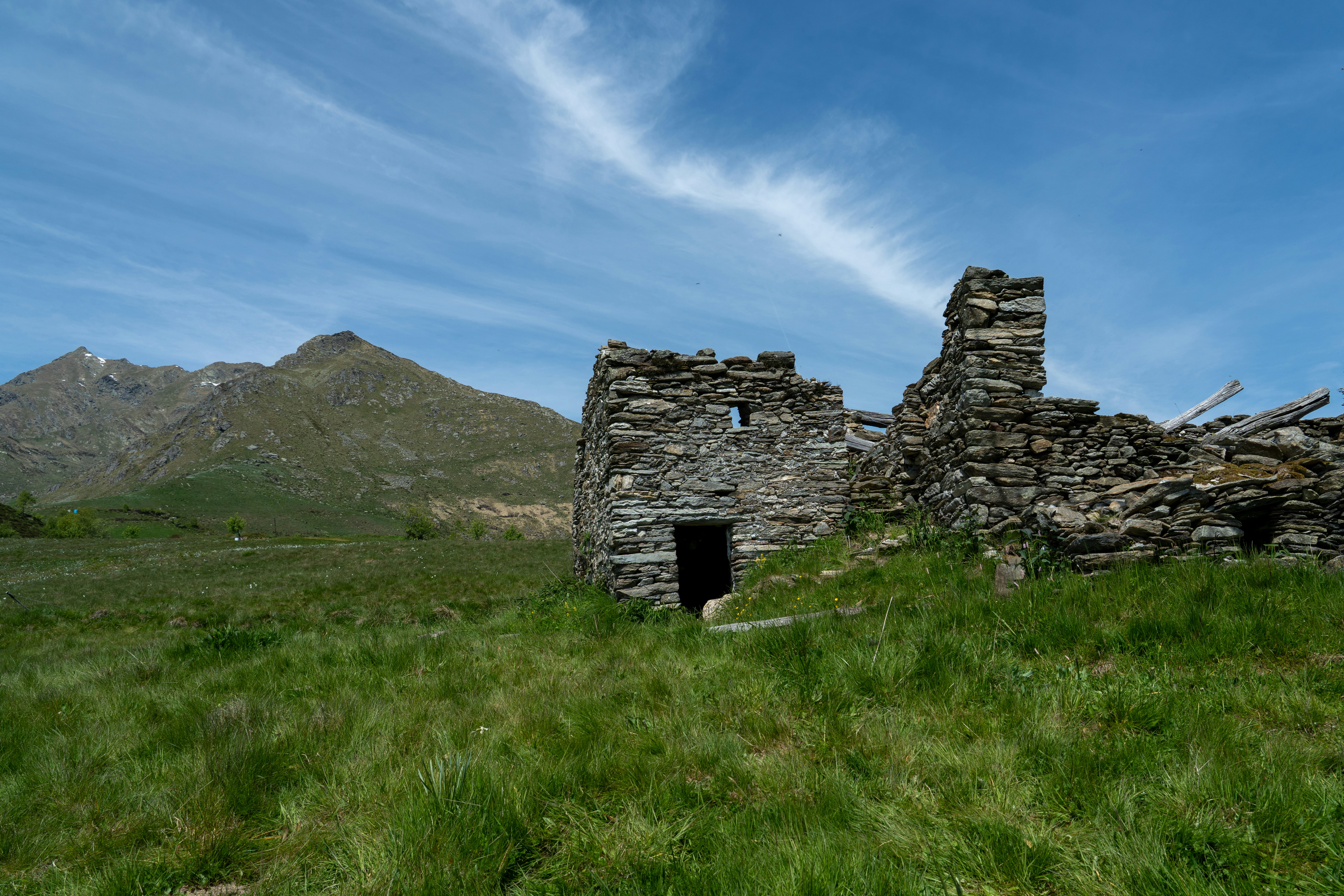 Old stone ruins in a grassy field with a mountain