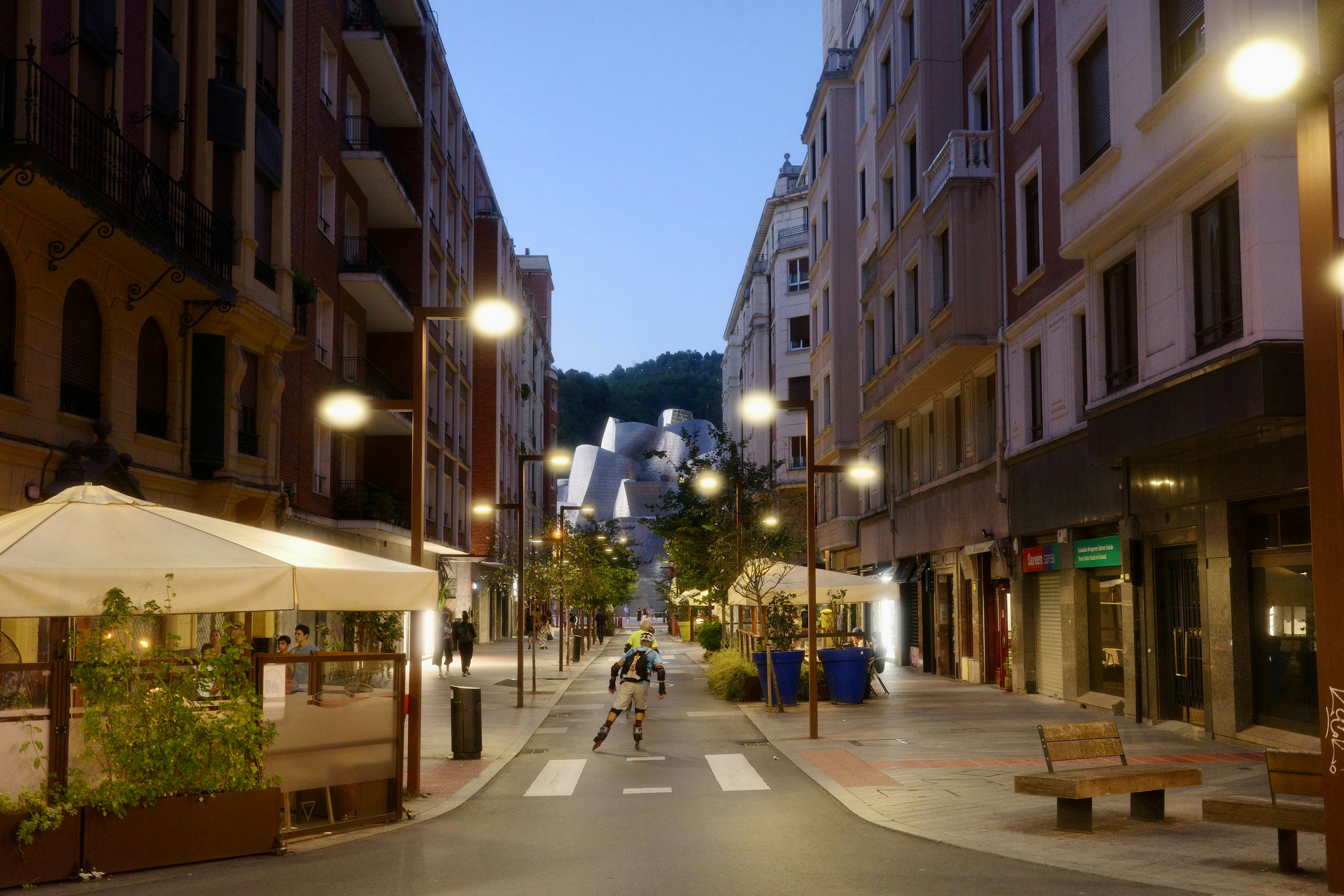 Urban street scene at night with illuminated buildings and people