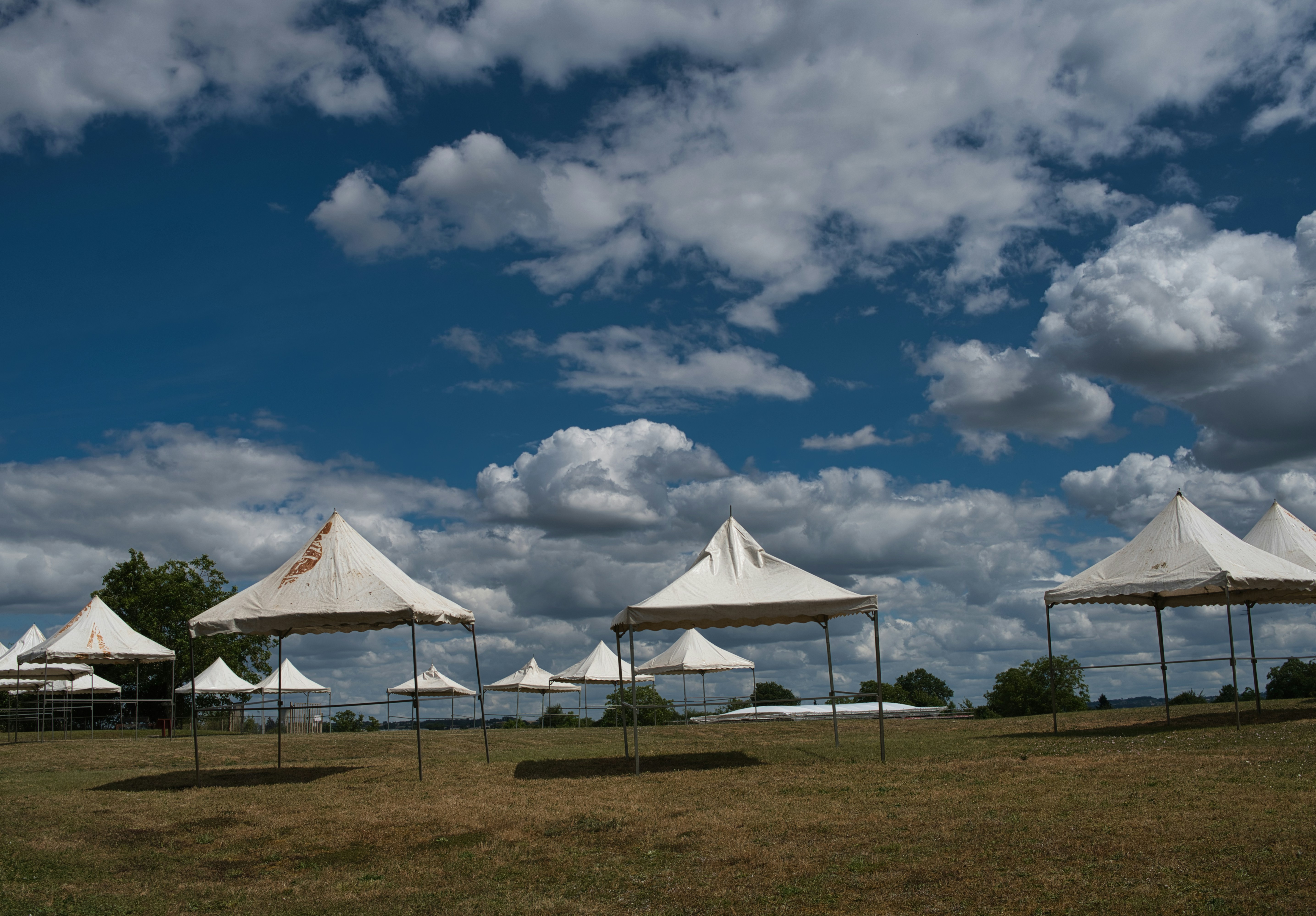 White tents in a dry field under a cloudy sky.
