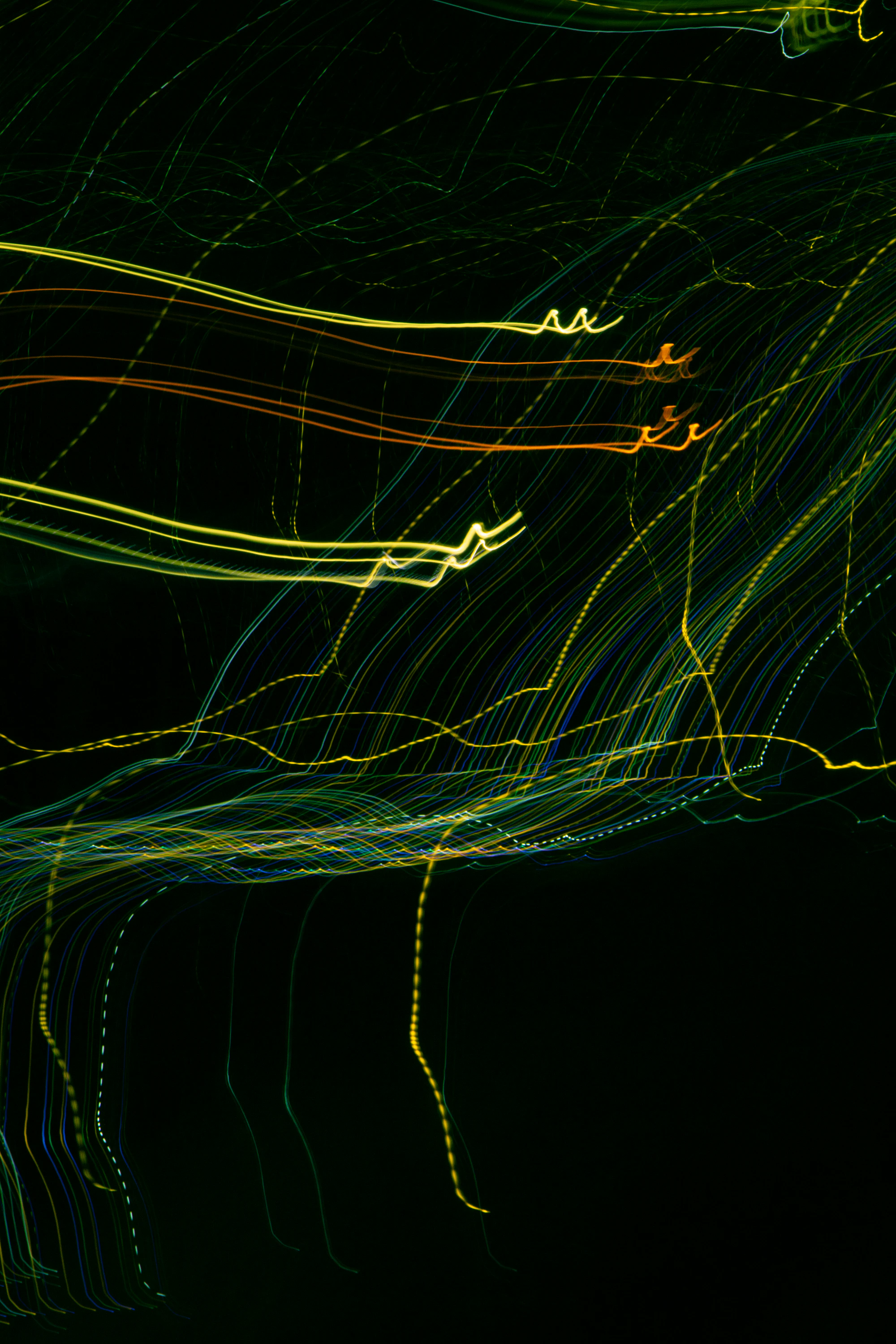 Green and yellow light trails curving across a dark background