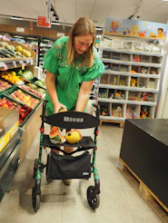 Woman places fruit on walker in supermarket.
