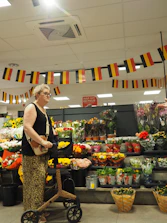 Elderly woman with rollator shopping for flowers in a store.